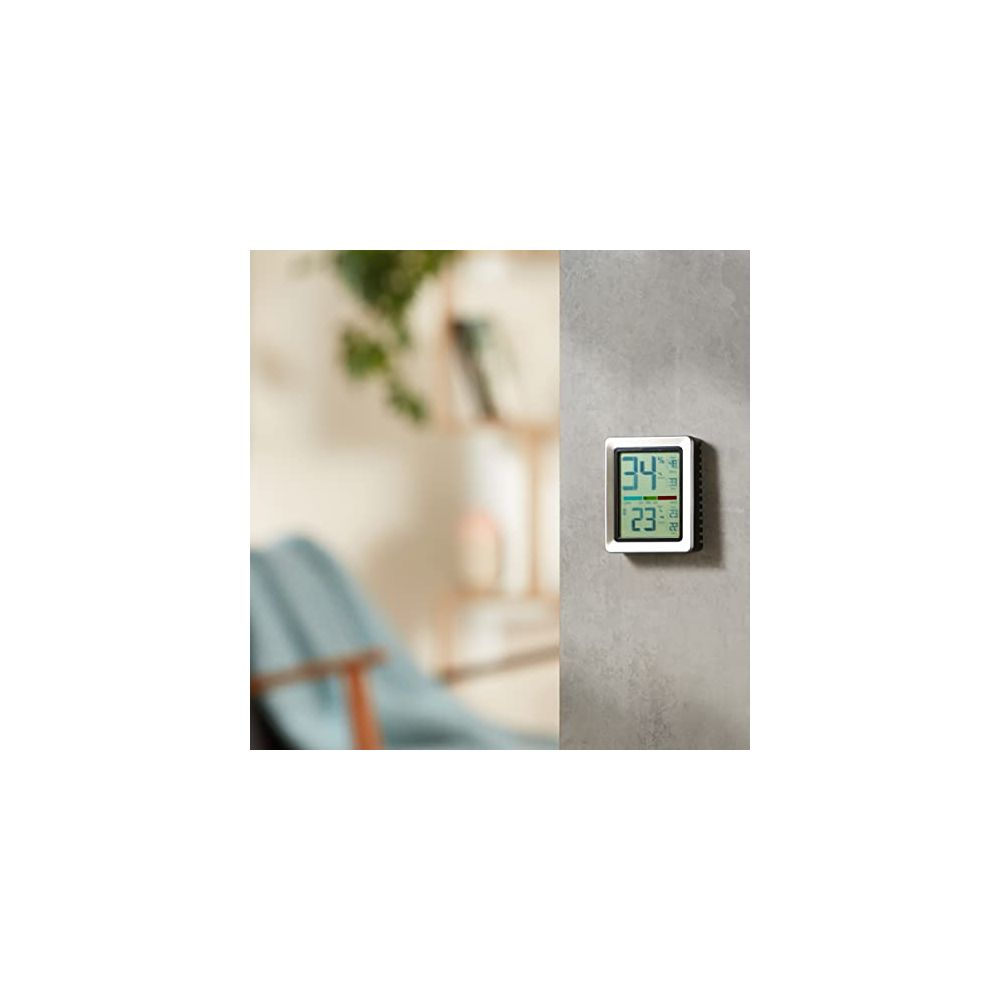 Ein weißer Digitalthermometer mit silbernem Rahmen an einer Wand.