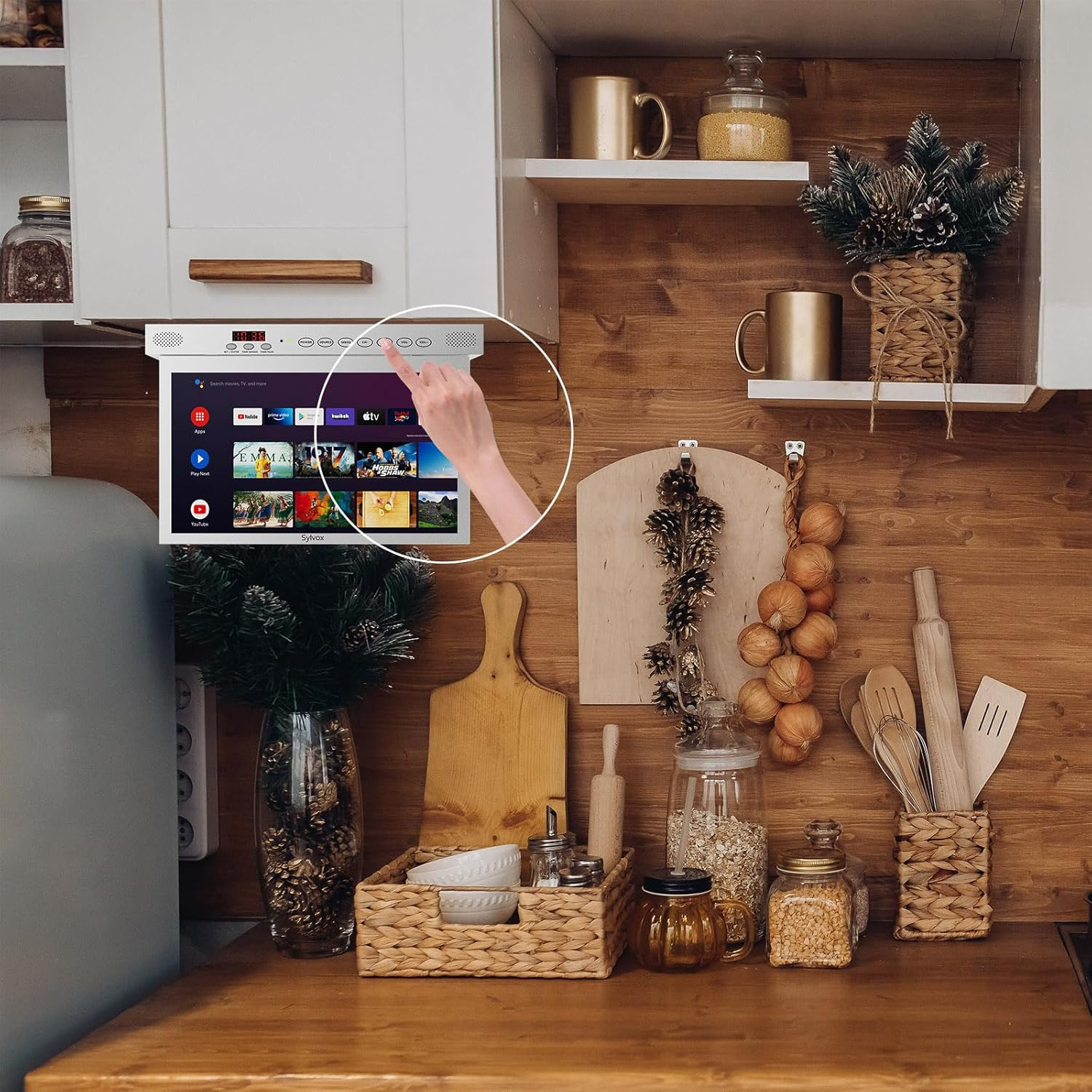 Una mano toca una pantalla con menús y aplicaciones en una cocina.