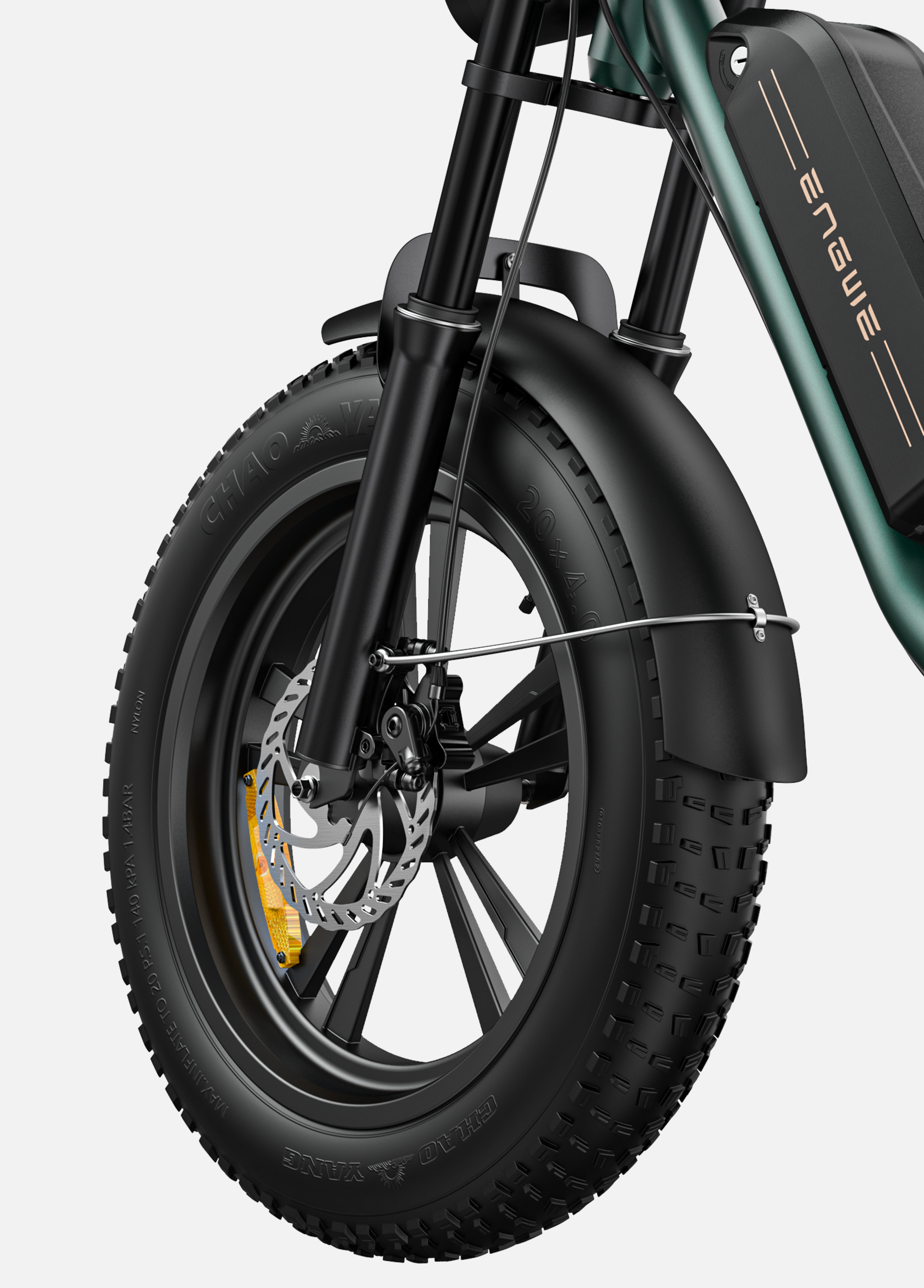 Primer plano de una e-bike verde con neumático ancho, freno de disco y suspensión.