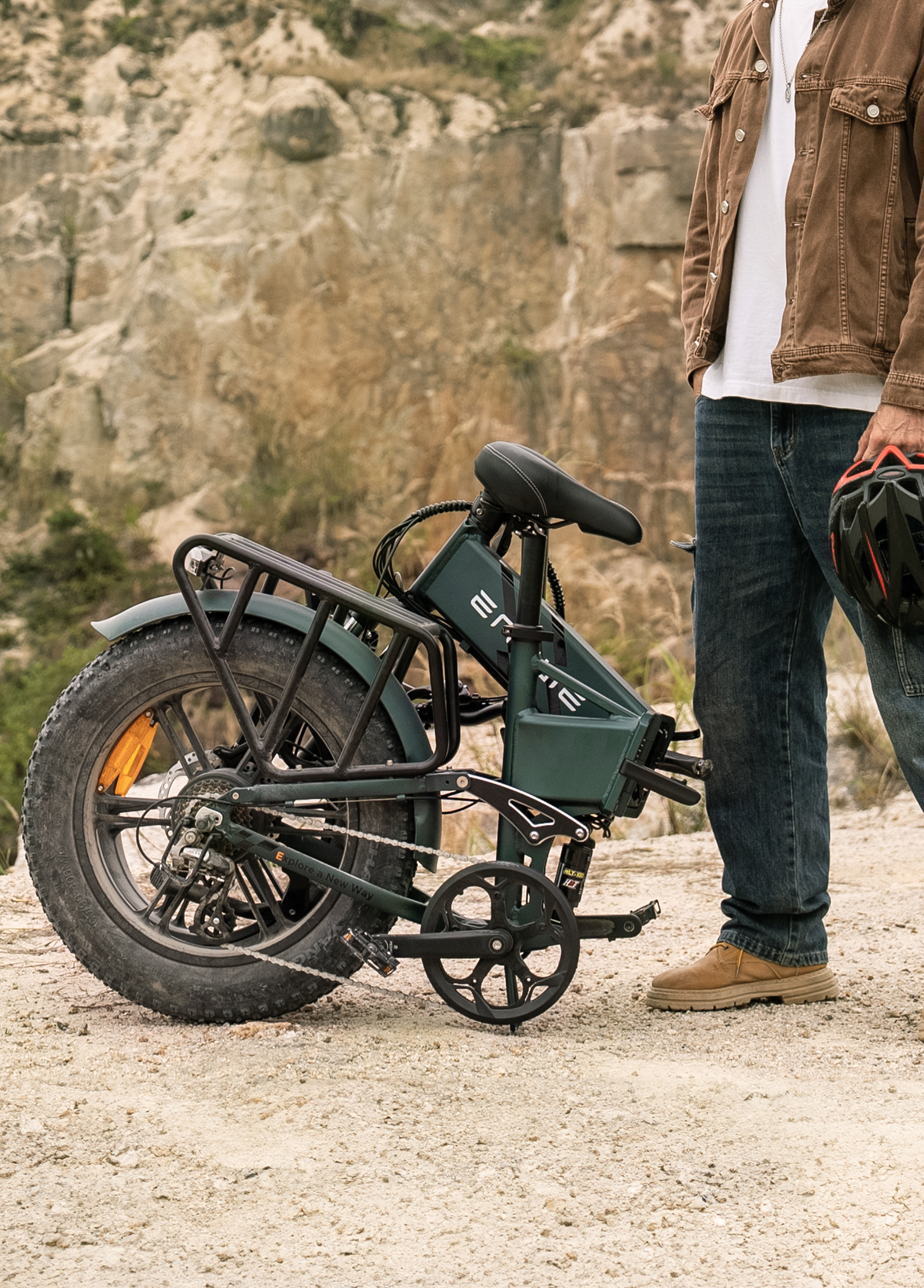 Ein Mann in Jeans und brauner Jacke steht neben einem grünen E-Bike im Freien.
