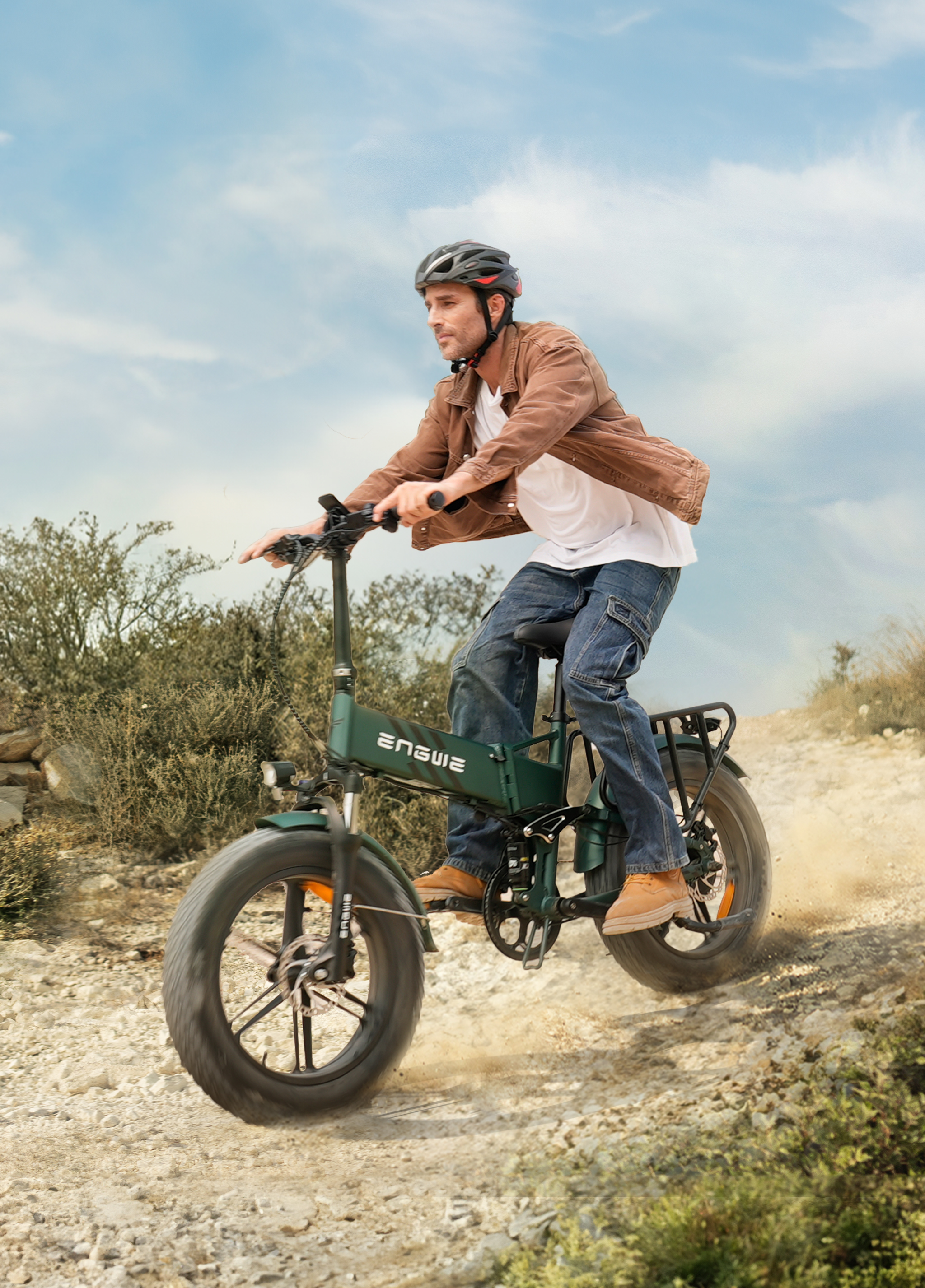 Mann fährt ein grünes E-Bike auf einem Feldweg, Staub wirbelt auf.