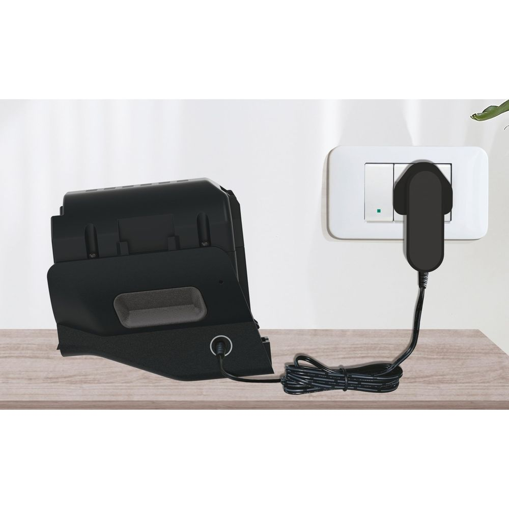 Czarna ładowarka na drewnianym stole, podłączona do białego gniazdka.