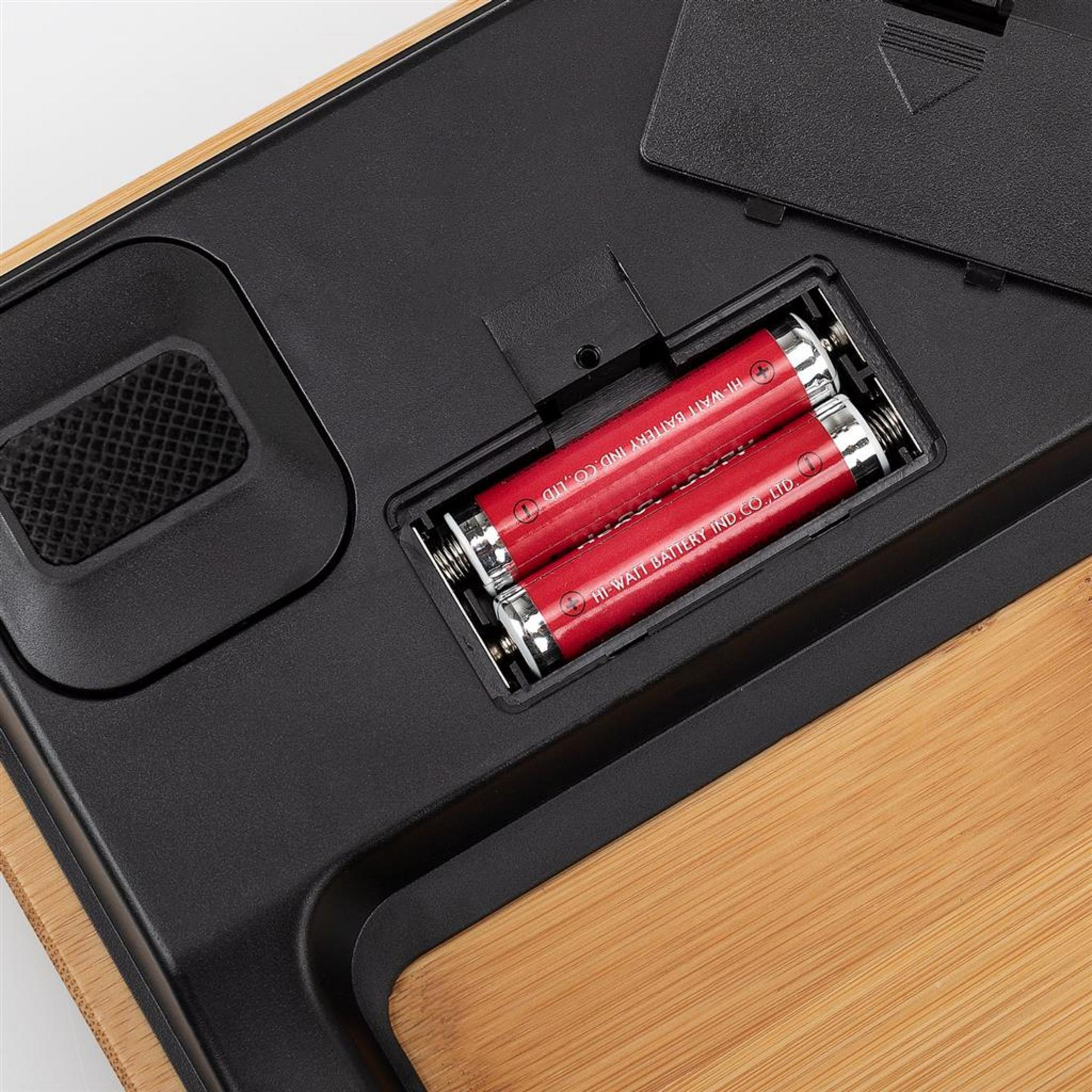 Dwa czerwone akumulatory w komorze baterii z czarnymi stykami.