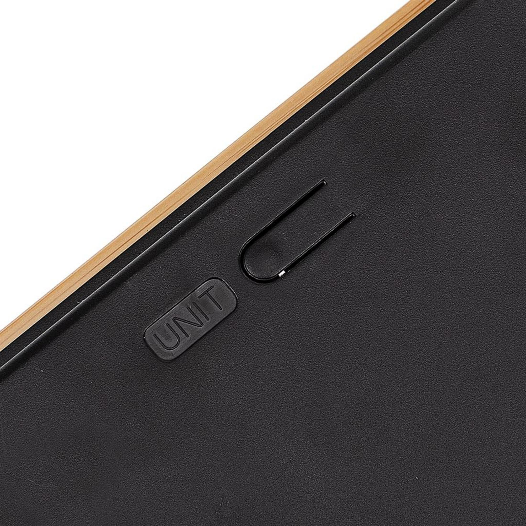 Zbliżenie spinacza w kształcie litery U na czarnej, teksturowanej powierzchni.