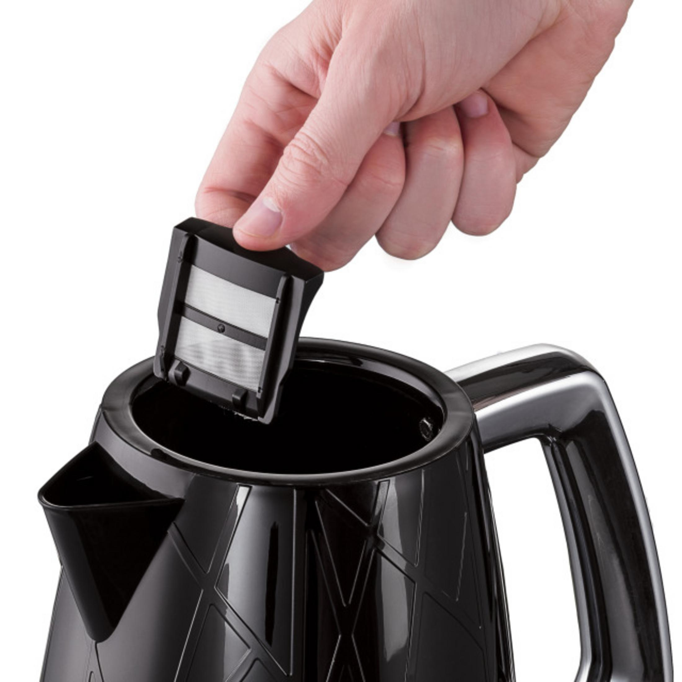 Une main insère un filtre noir dans une bouilloire.