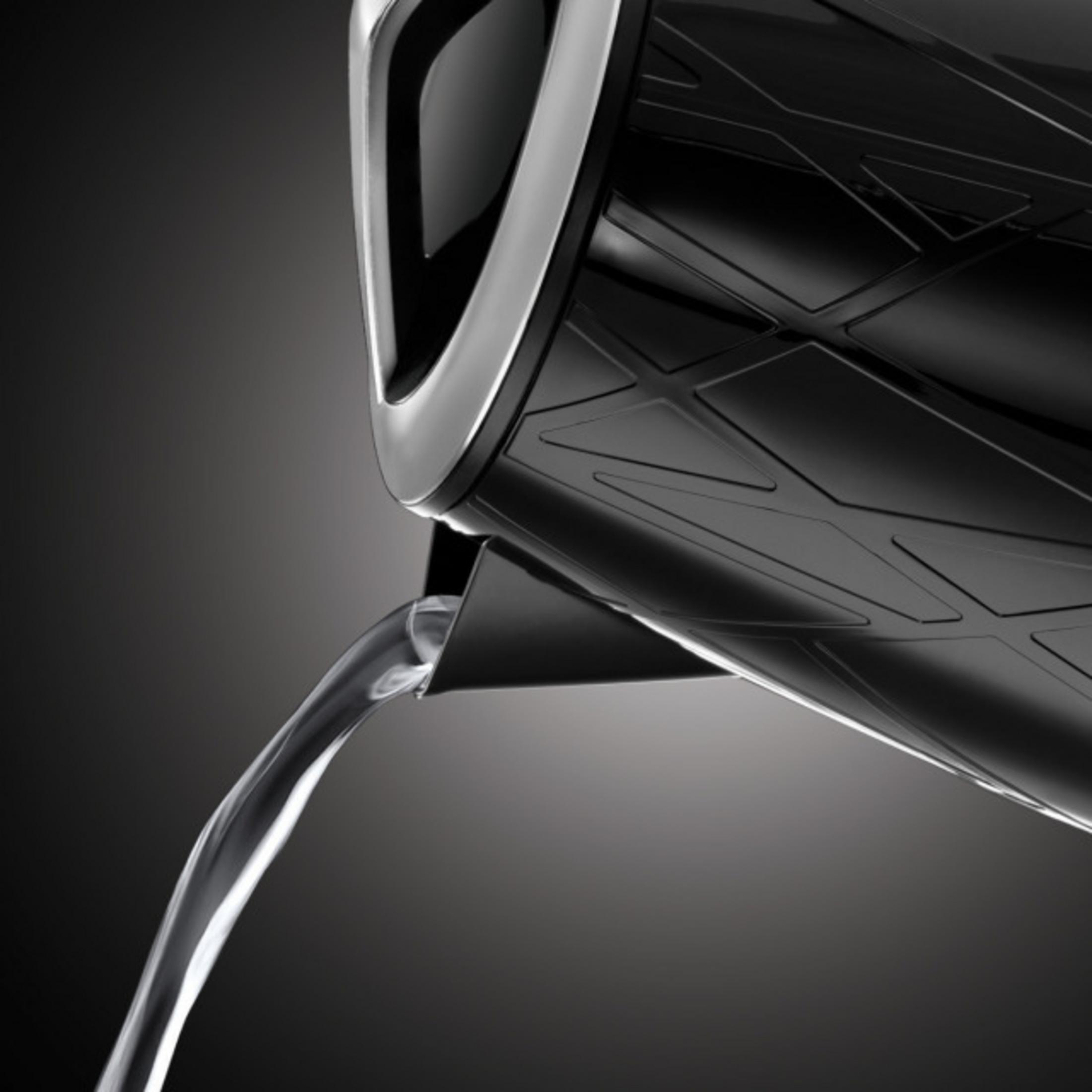 De l'eau coule d'une bouilloire noire sur fond sombre.