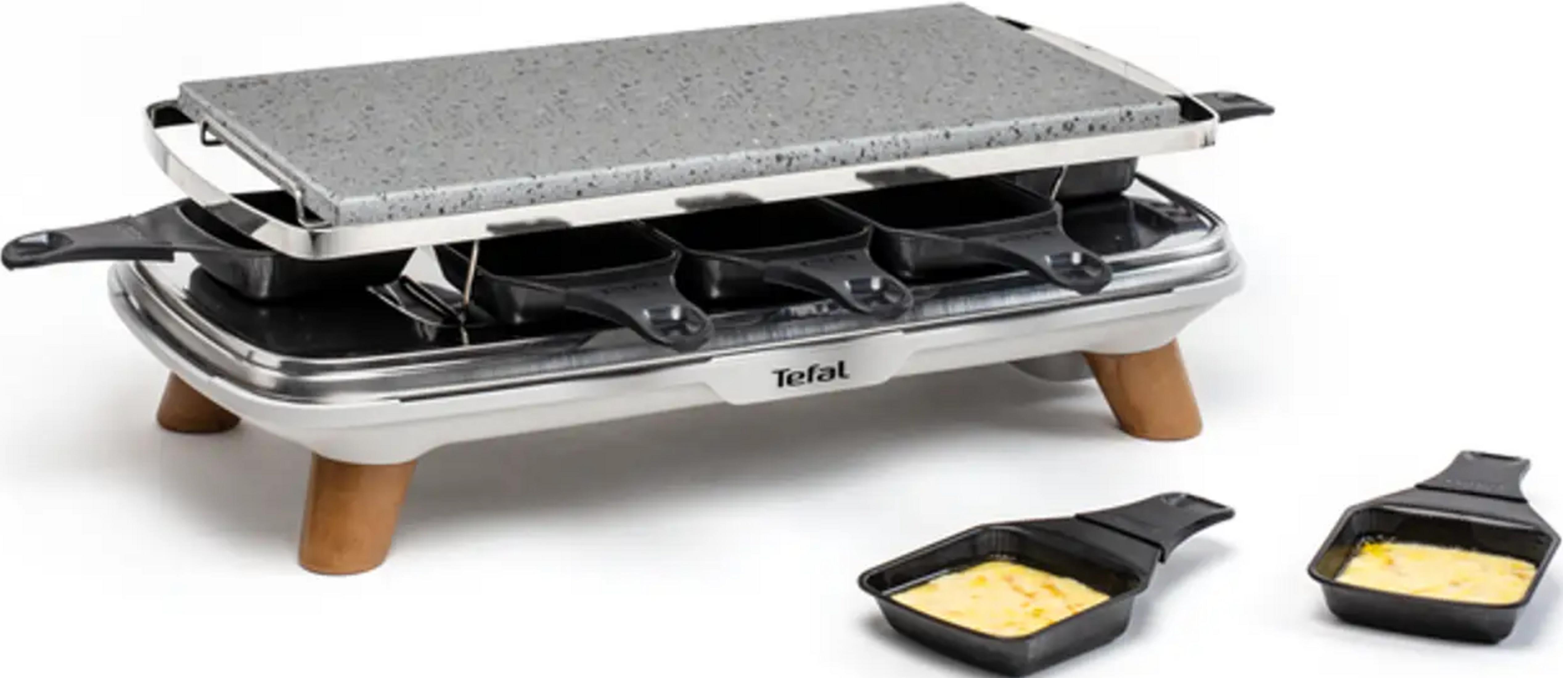 Ein Raclette-Grill mit Steinplatte und vier Pfännchen, zwei davon gefüllt.