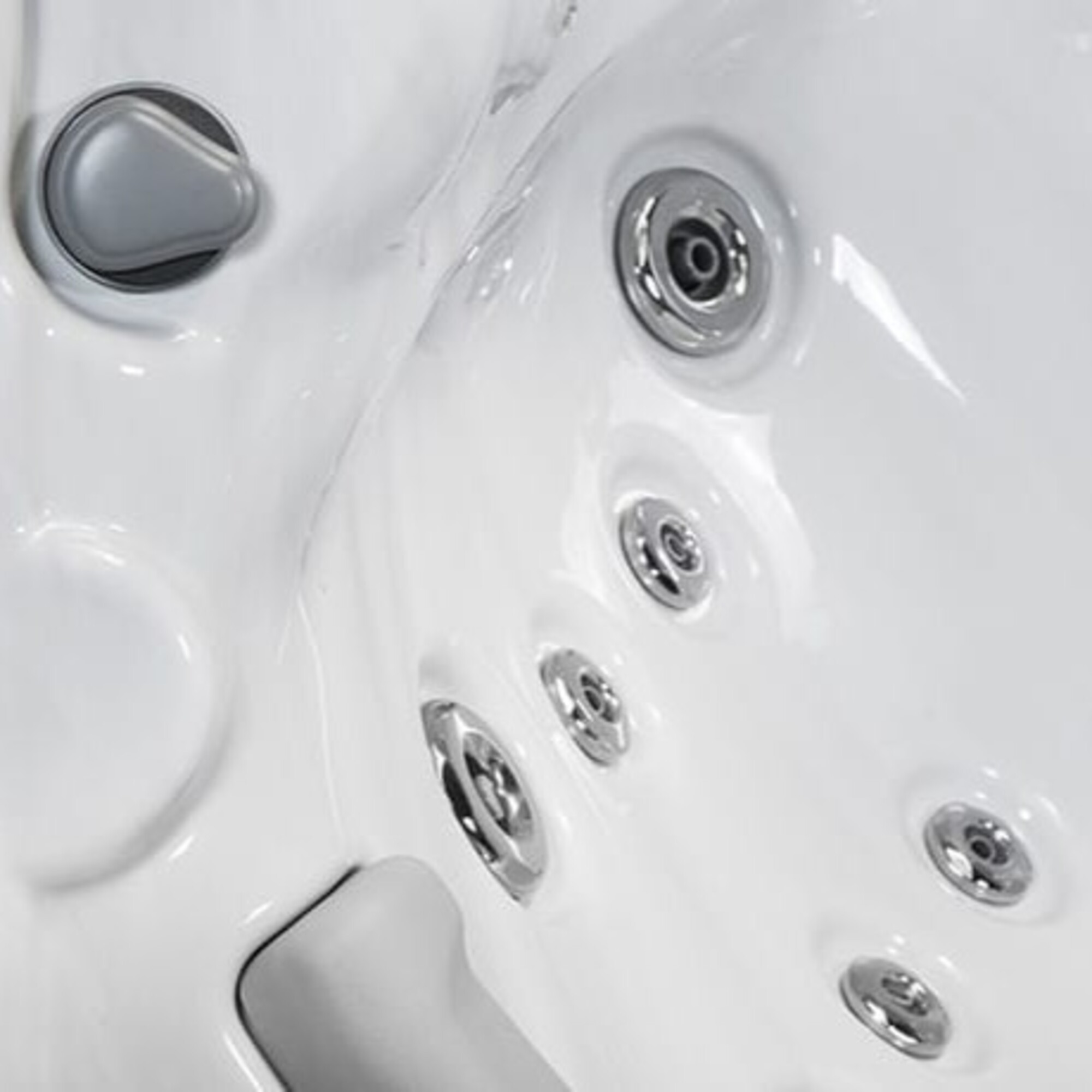 Primer plano de una bañera blanca con varios chorros cromados y un mando gris.