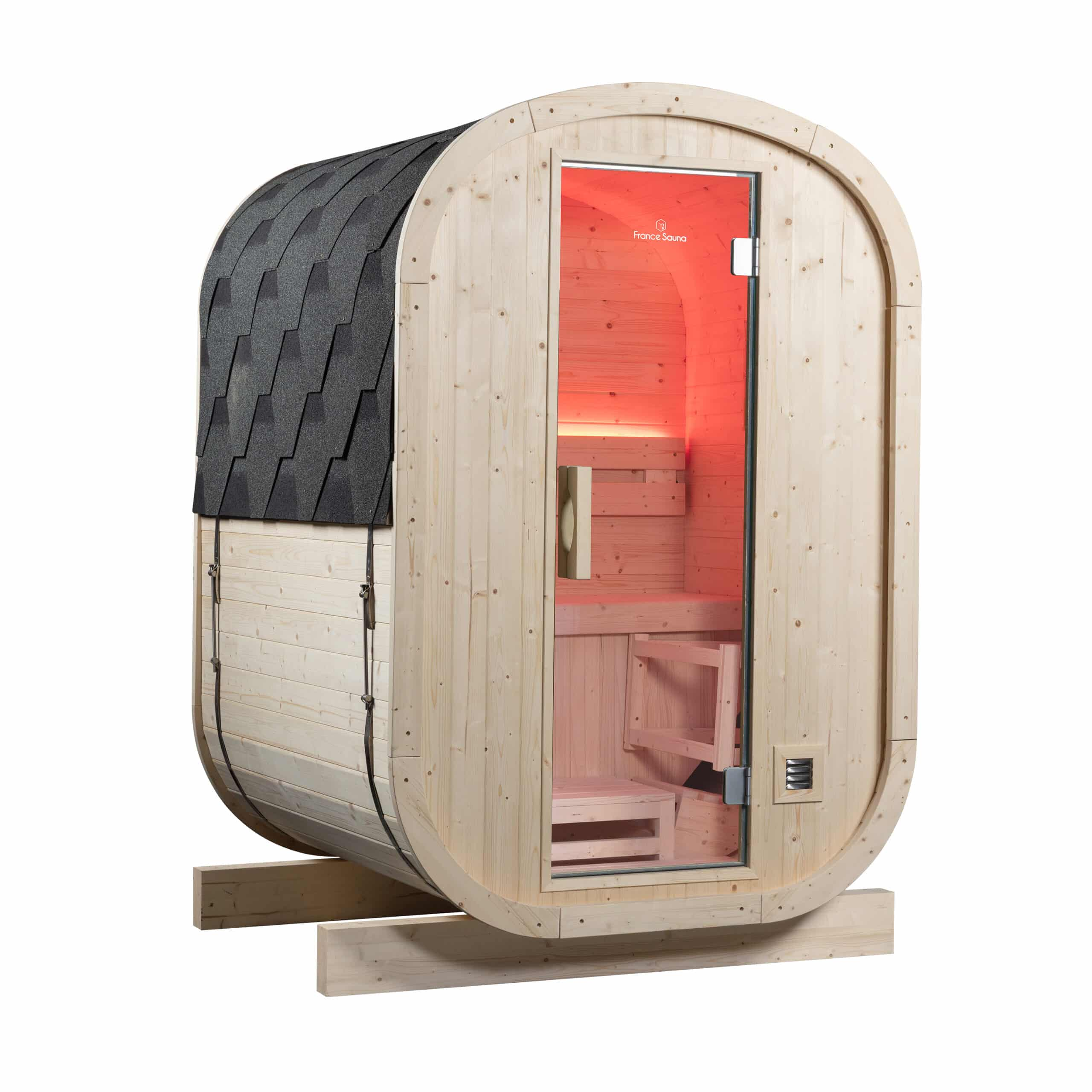 Una sauna de barril de madera con puerta de cristal e iluminación interior roja.