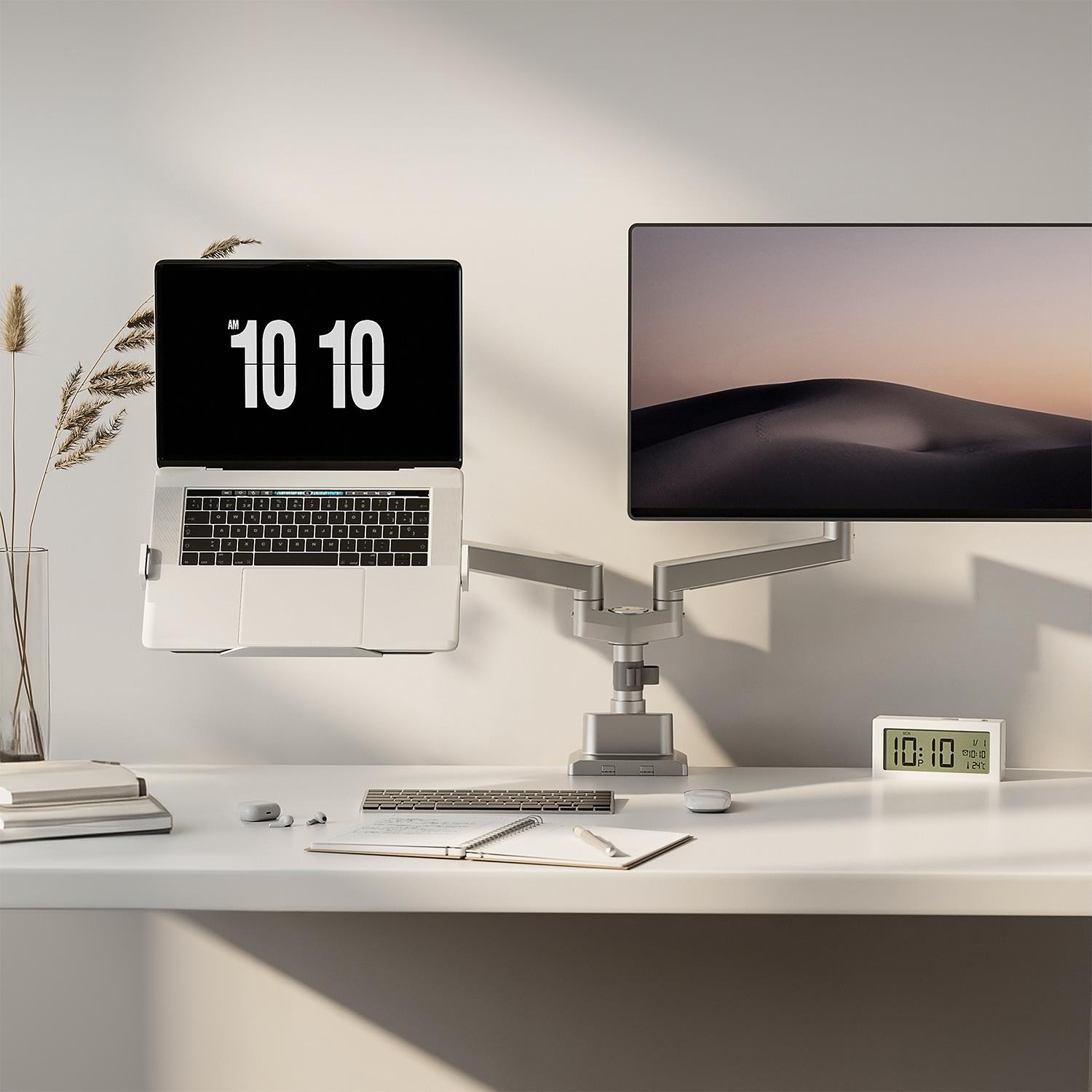 Laptop, monitör, klavye, fare ve saatli modern masa kurulumu.