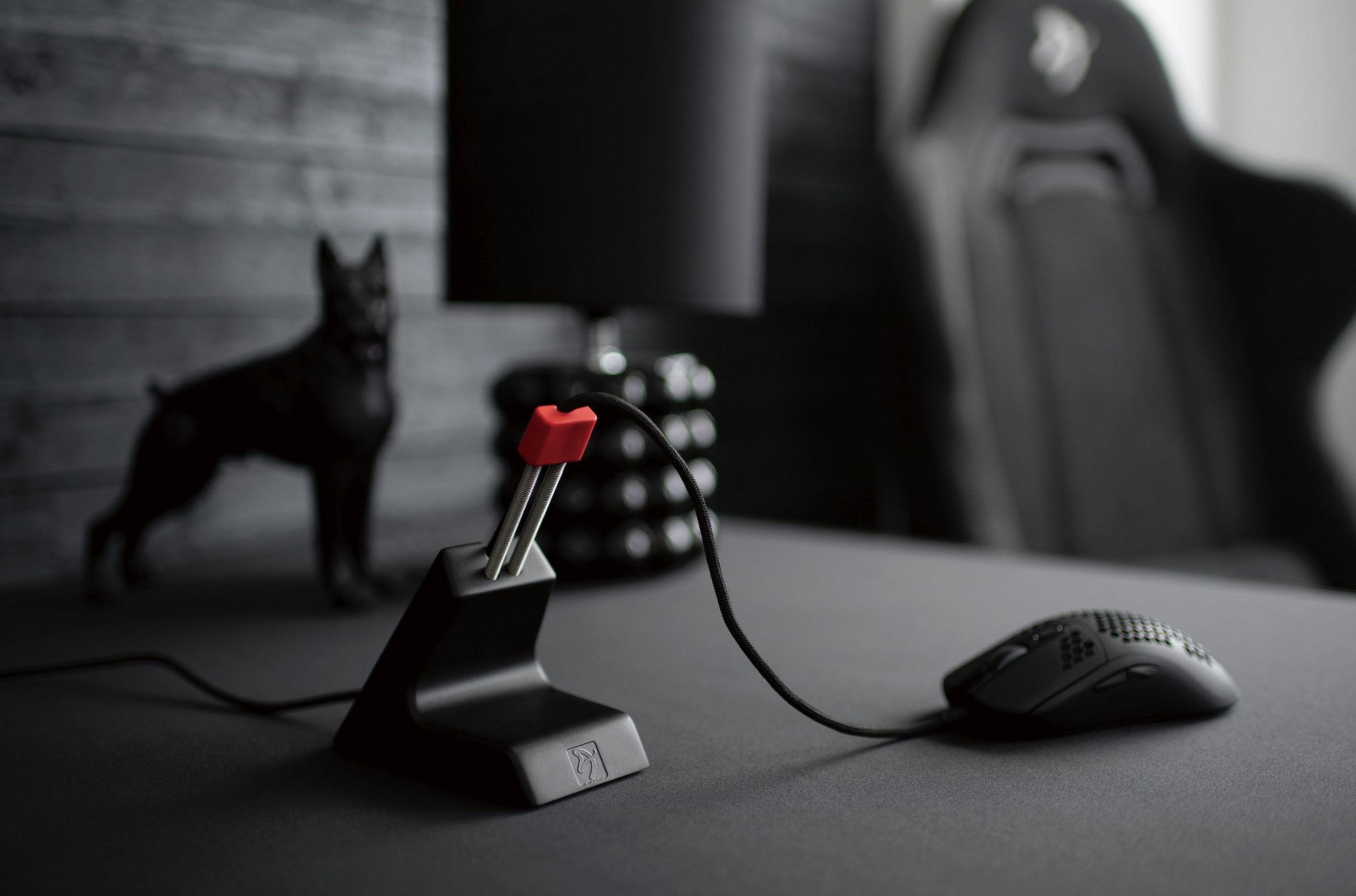 Un supporto per cavo mouse da gioco nero con punta rossa e un mouse.