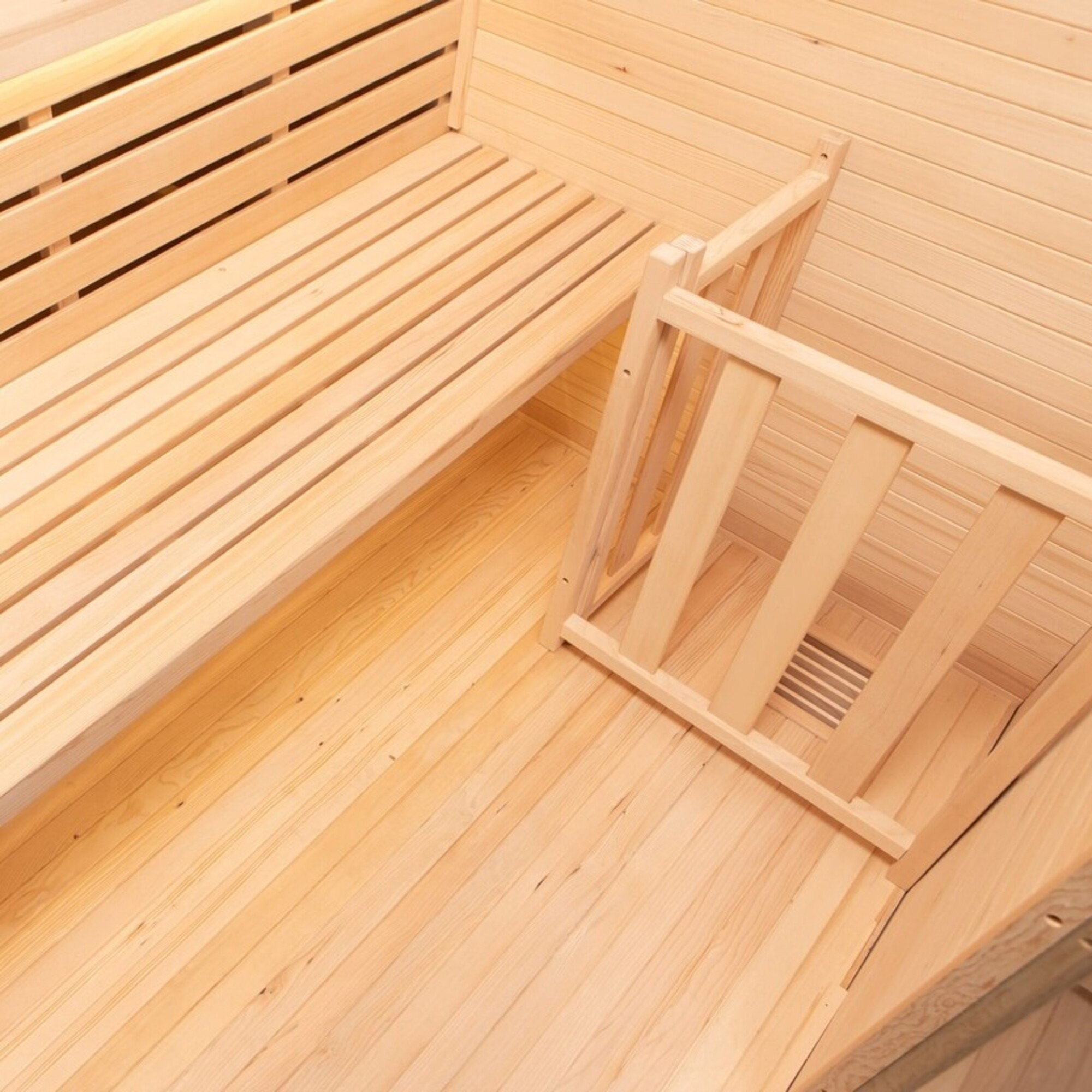 Sauna de madera con bancos y una pequeña valla de madera.
