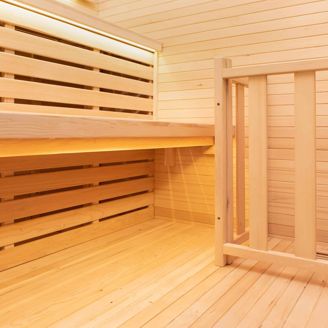 Interior de una sauna de madera con bancos y luz cálida.