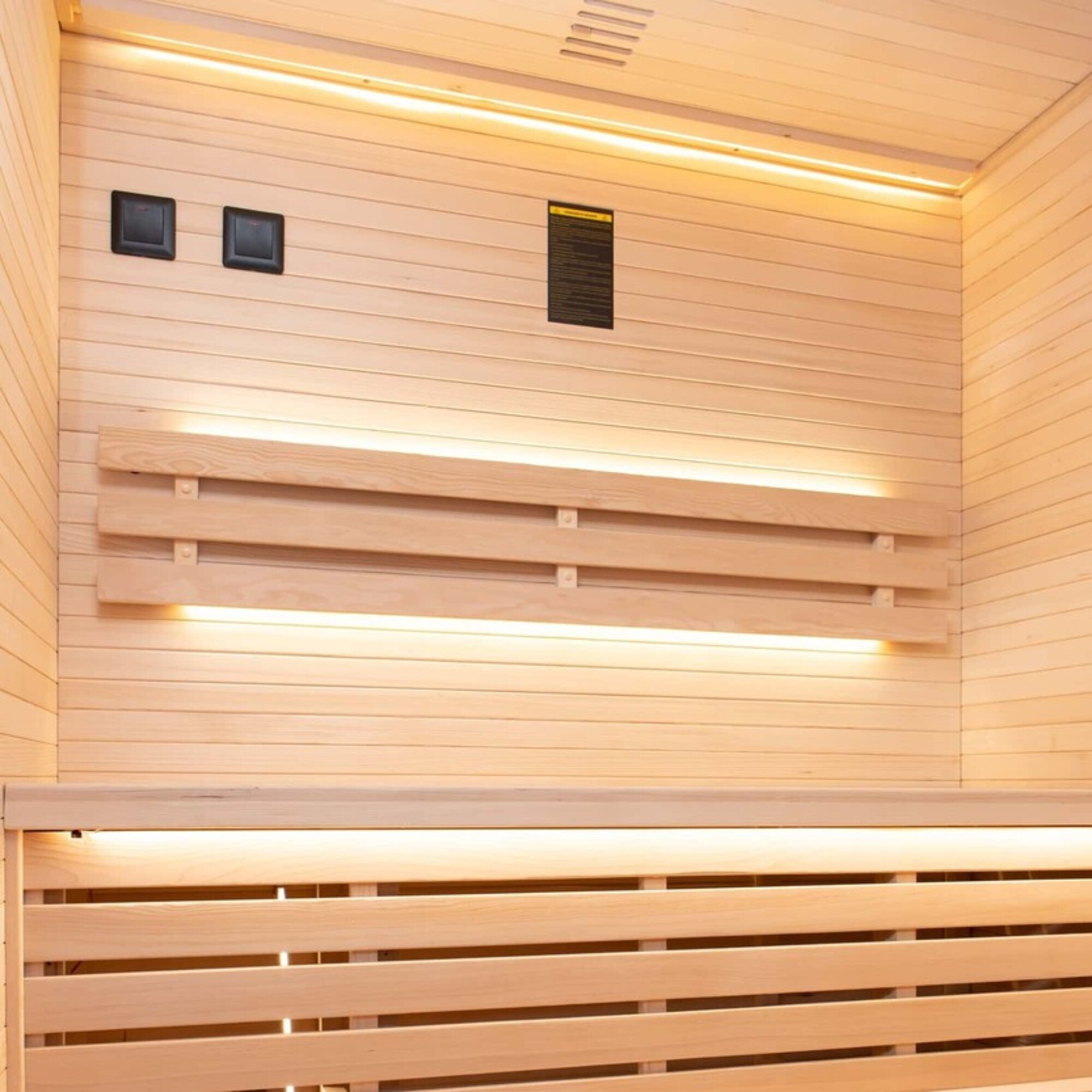 Sauna de madera con bancos y luz.