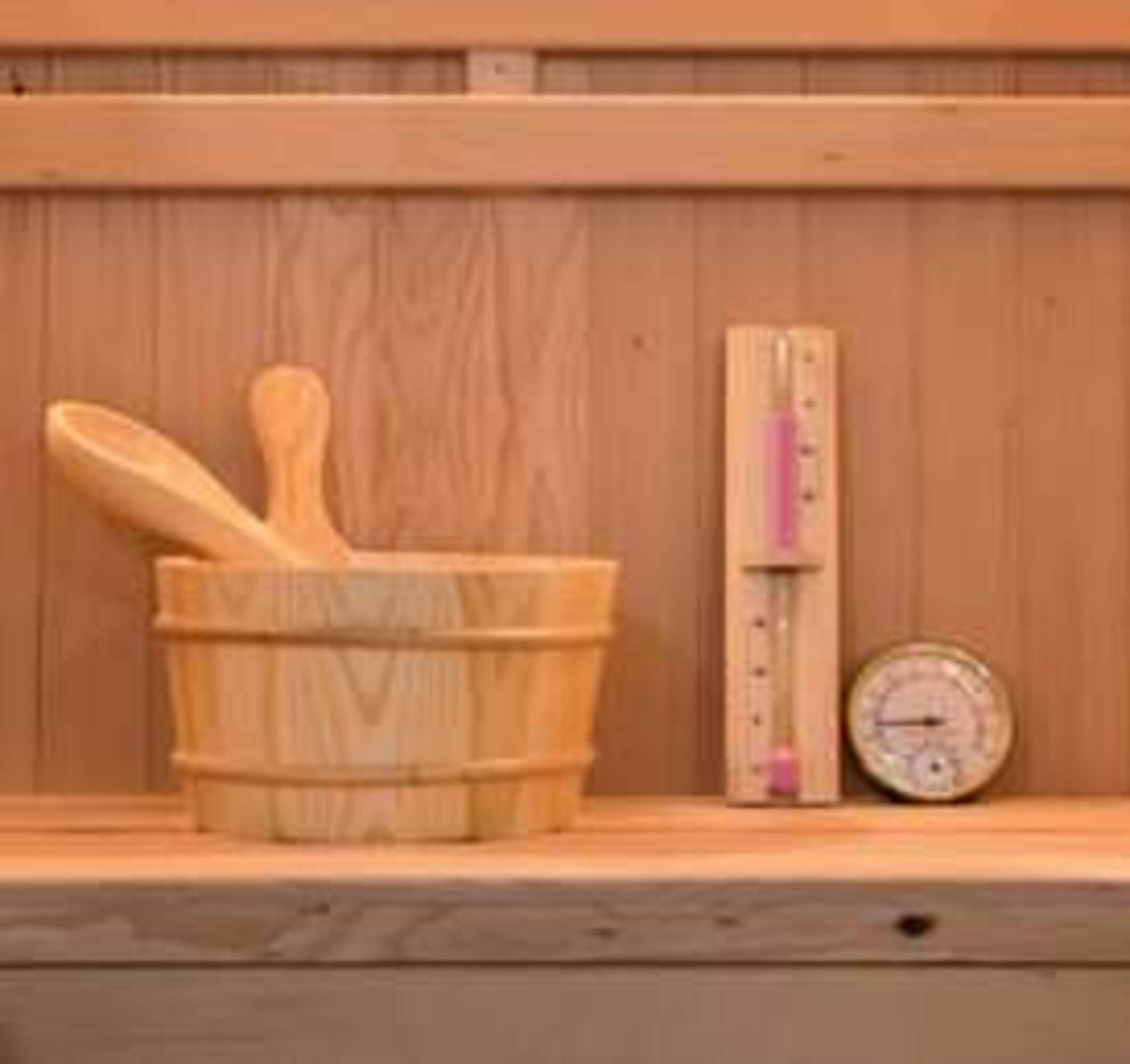 Cubo de madera con cucharón, termómetro e higrómetro en una sauna.