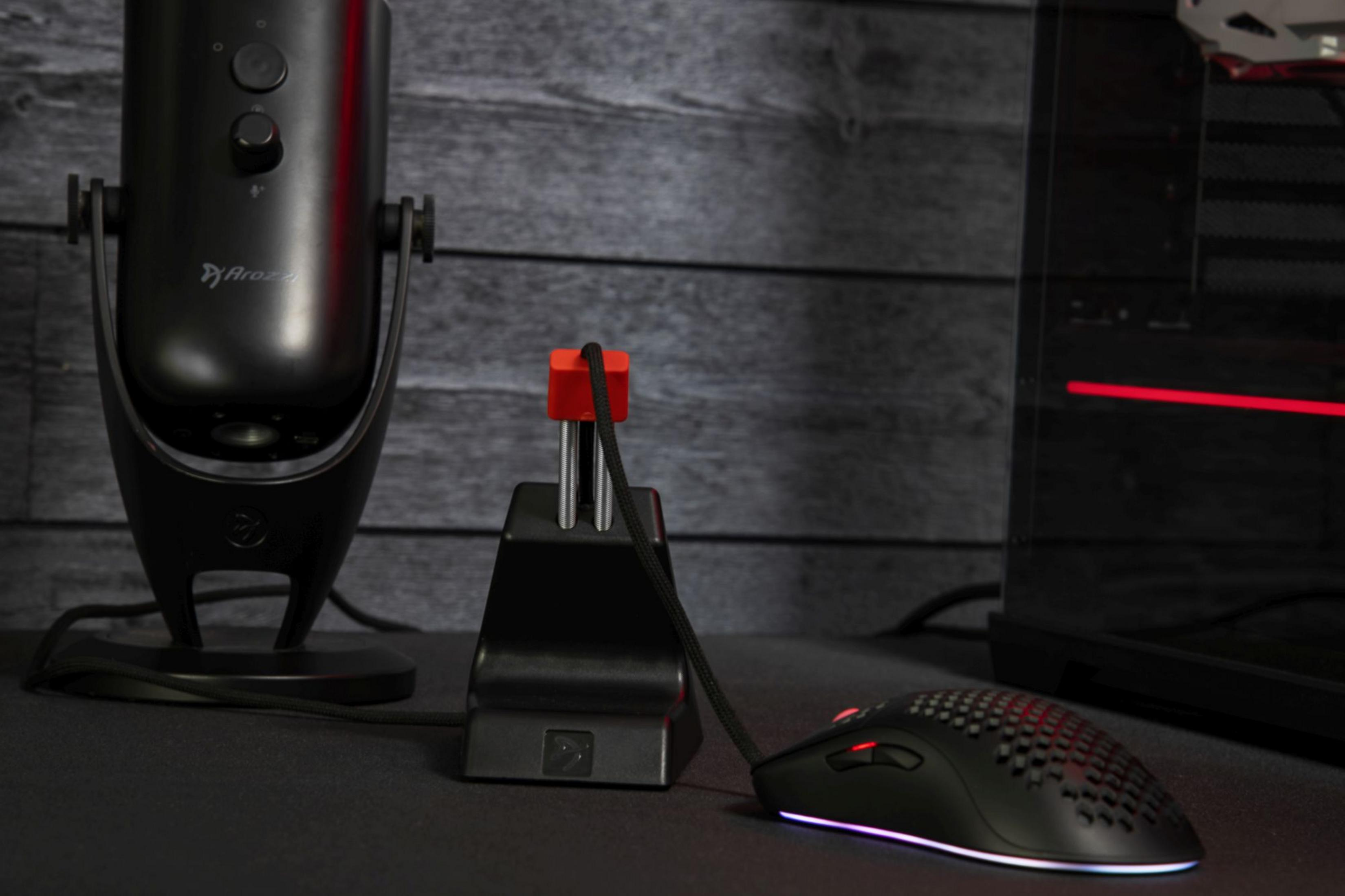 Microfono nero, bungee per mouse e mouse da gaming su superficie scura.