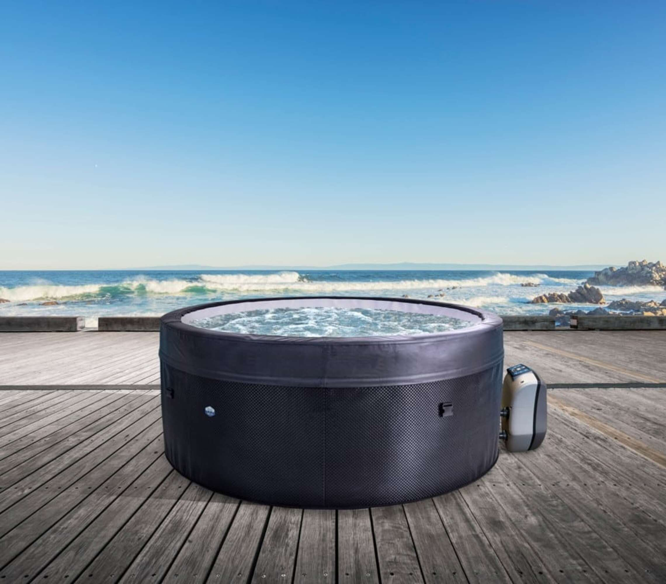 Un jacuzzi inflable está en una terraza de madera junto al mar.