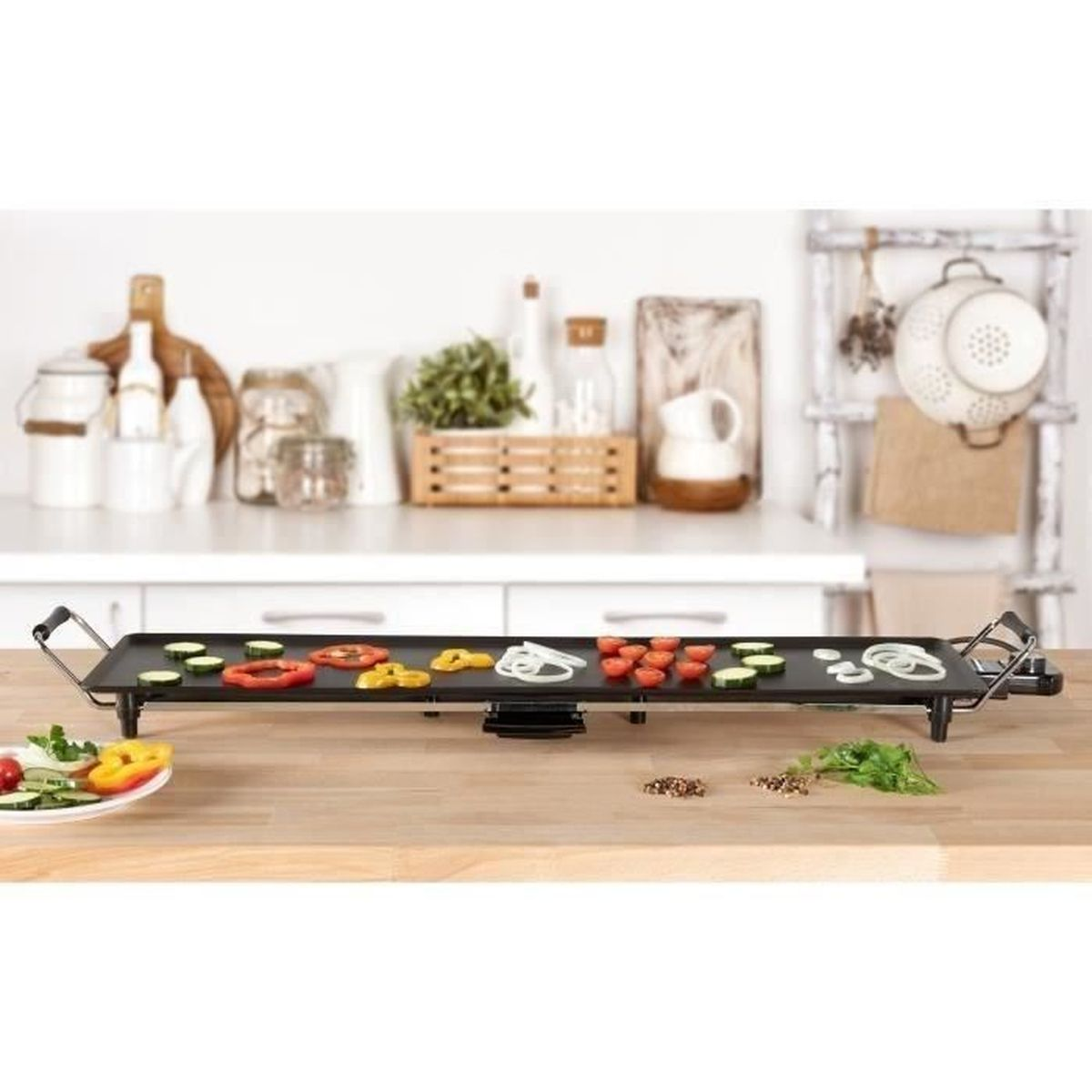 Een elektrische grillplaat met gesneden groenten erop, op een houten tafel.