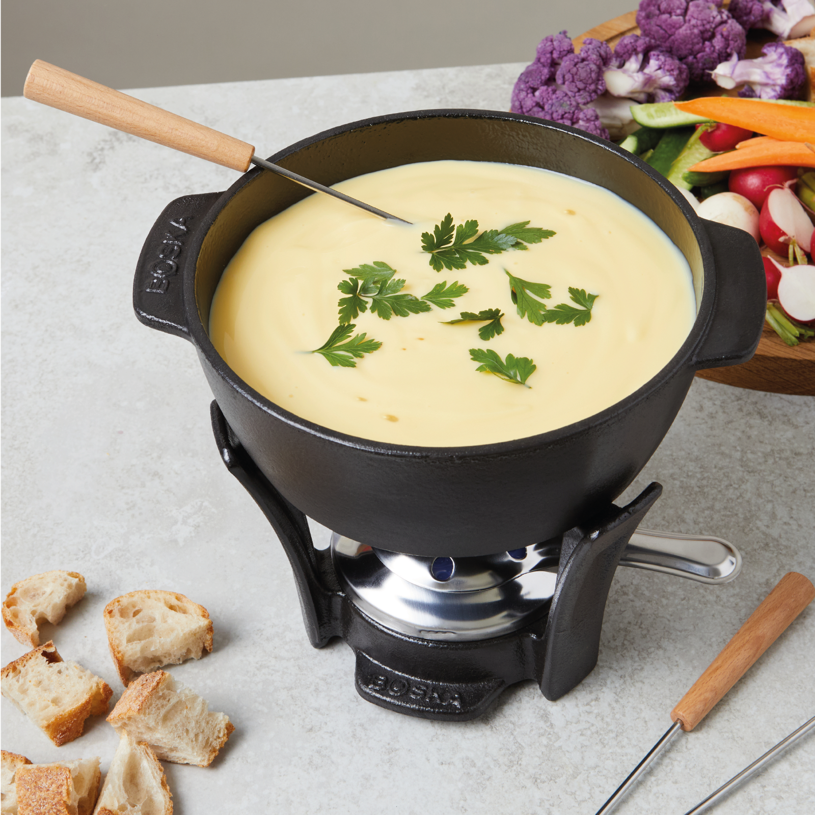 Ein Käsefondue-Topf mit Brot und Gemüse auf einem Tisch.