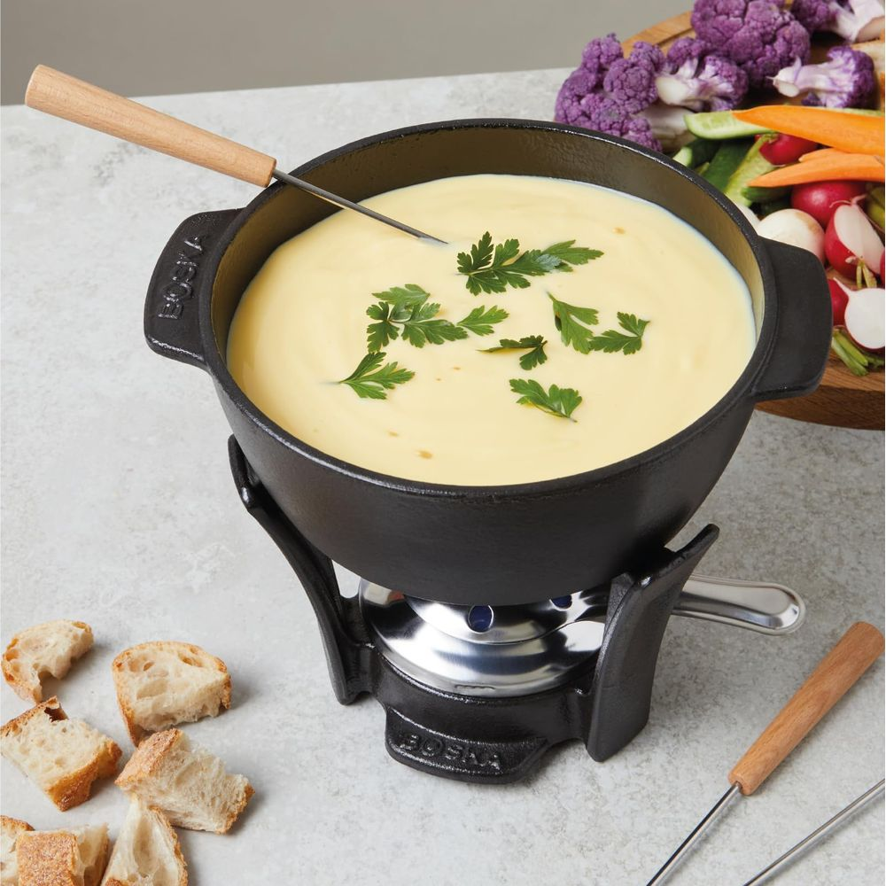 Ein Käsefondue-Topf mit Brot und Gemüse auf einem Tisch.
