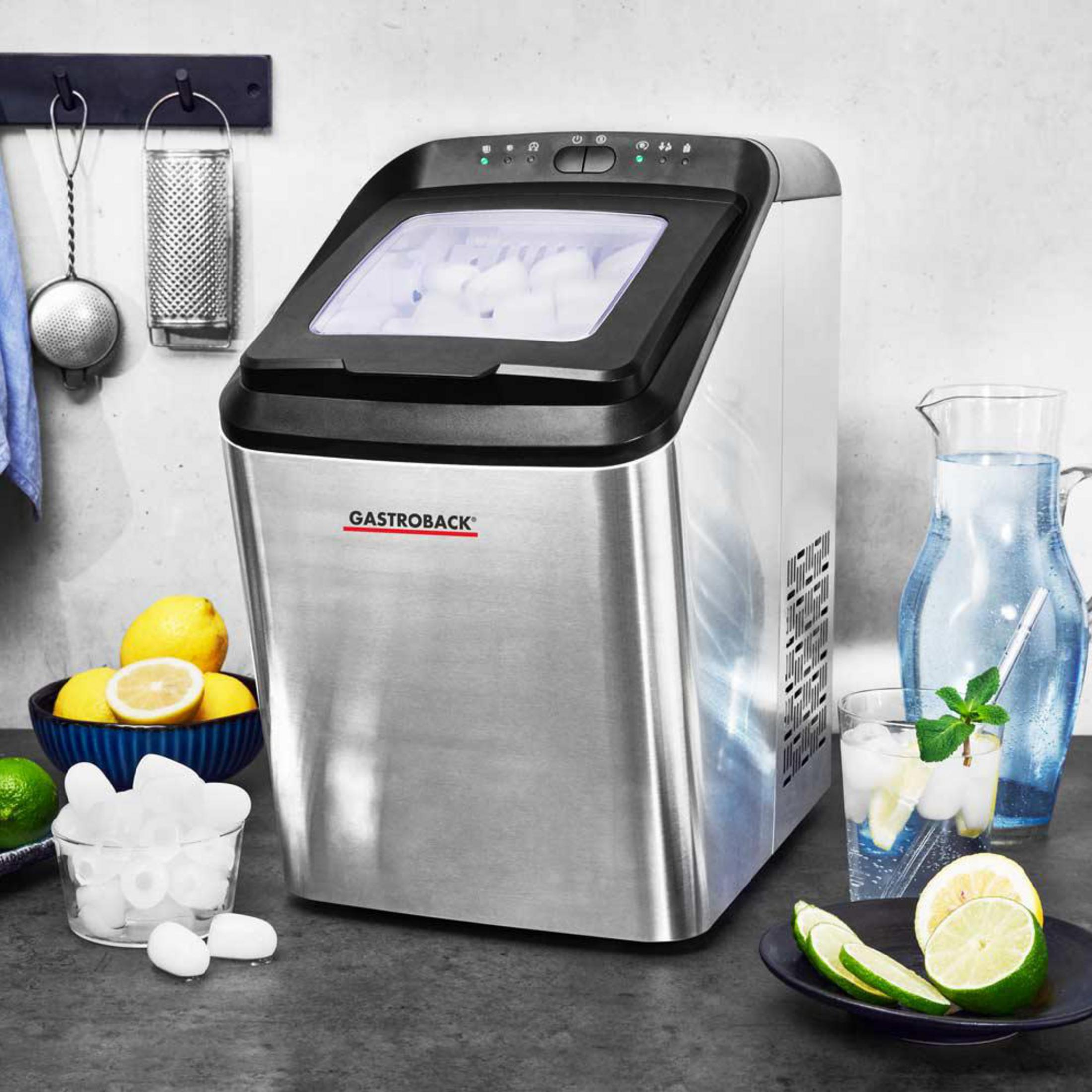 Edelstahl-Eismaschine mit Eiswürfeln, Zitronen, Limetten, Wasser und einem Krug.