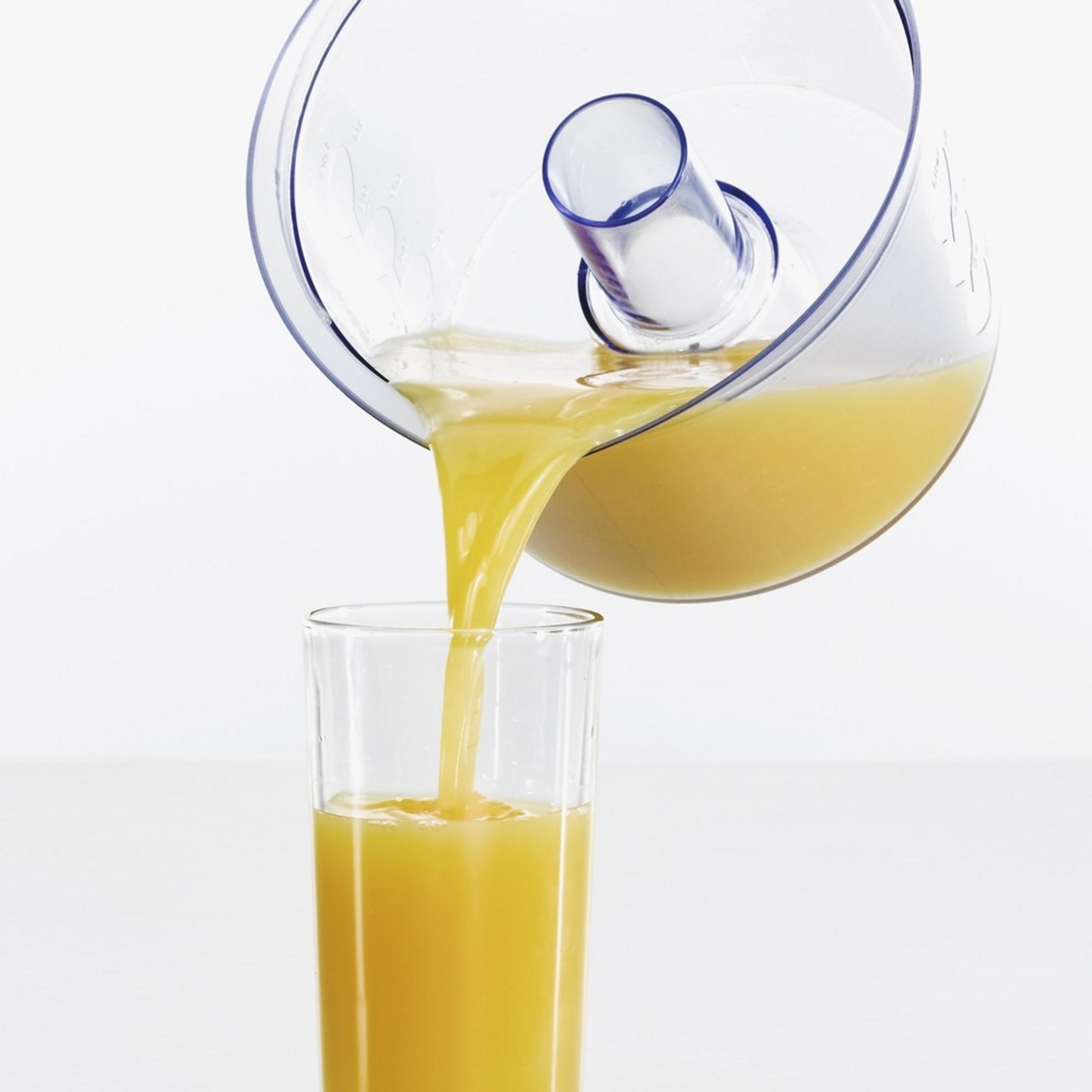 Il succo d'arancia viene versato da una brocca in un bicchiere.