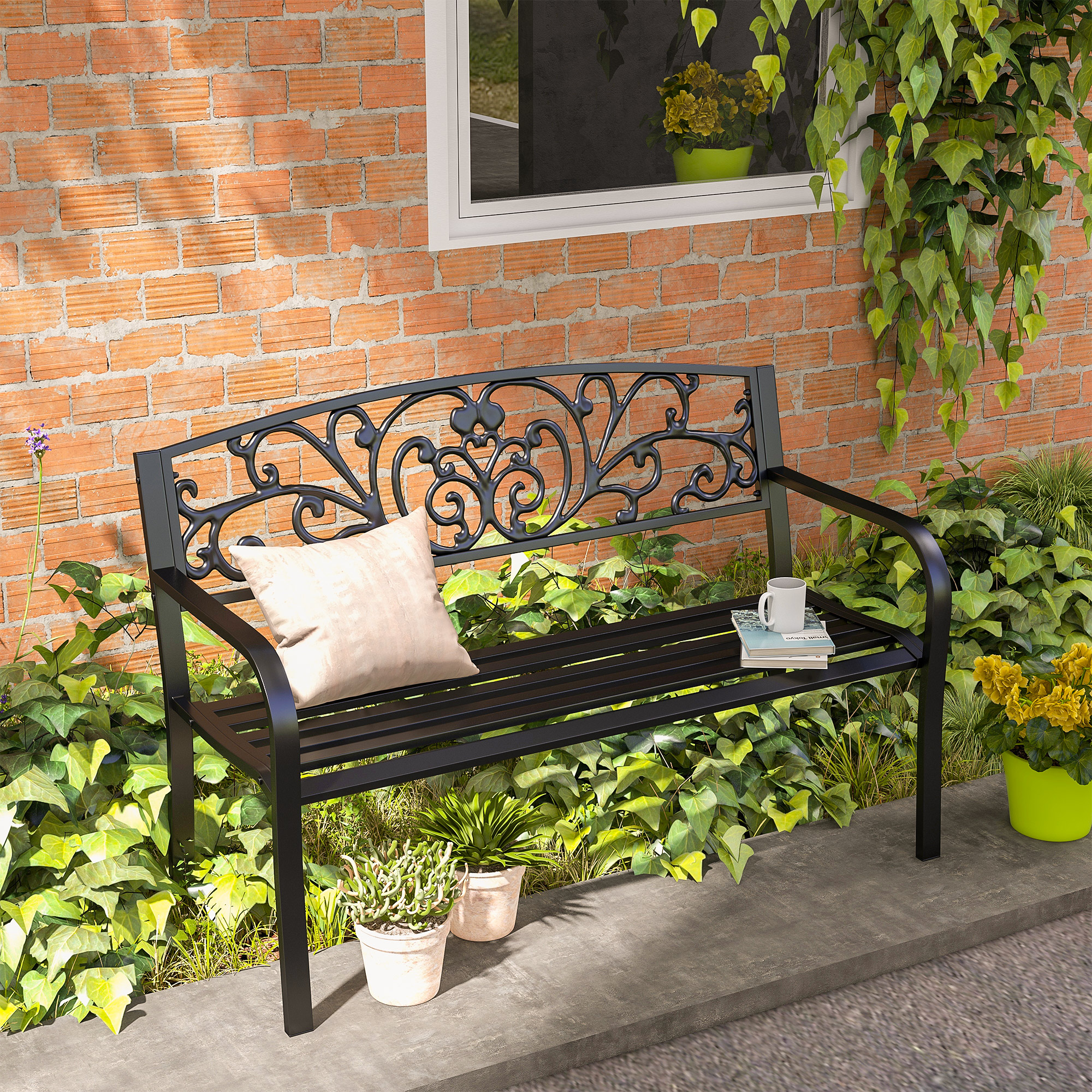 Una panchina da giardino nera siede di fronte a un muro di mattoni con piante verdi.