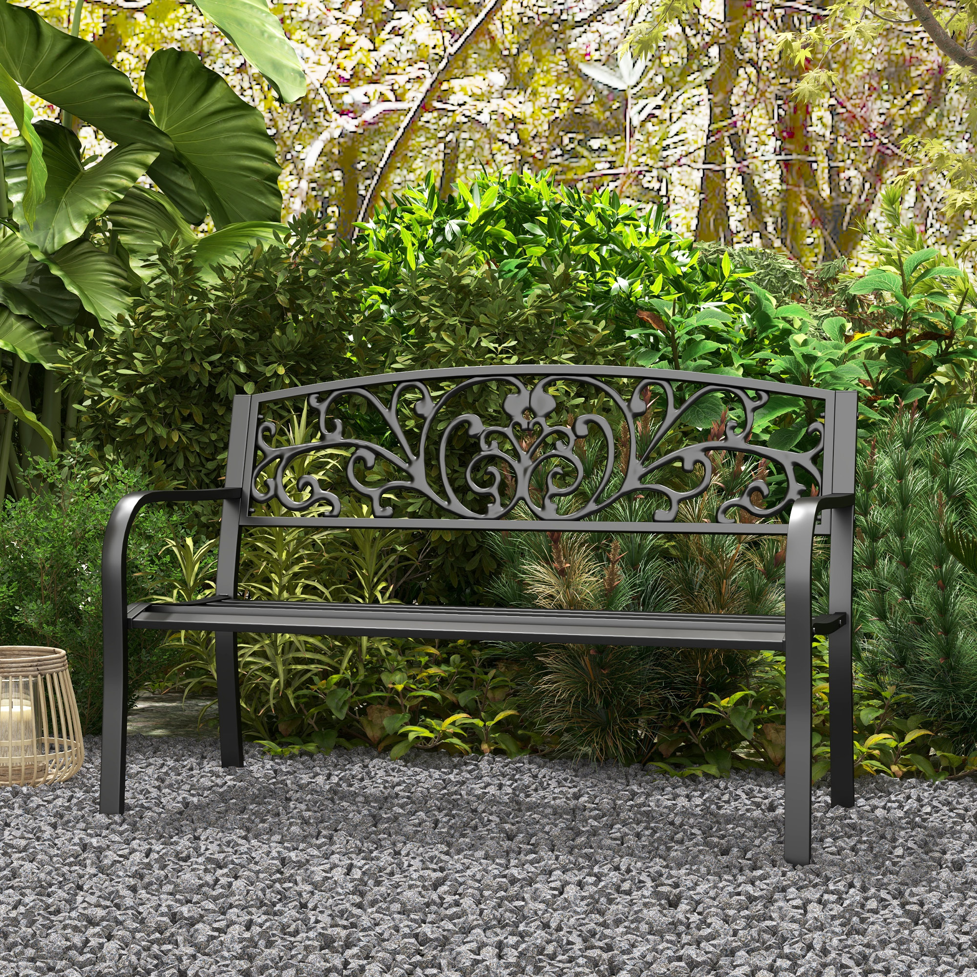 Una panchina da giardino nera su ghiaia davanti a verde lussureggiante.