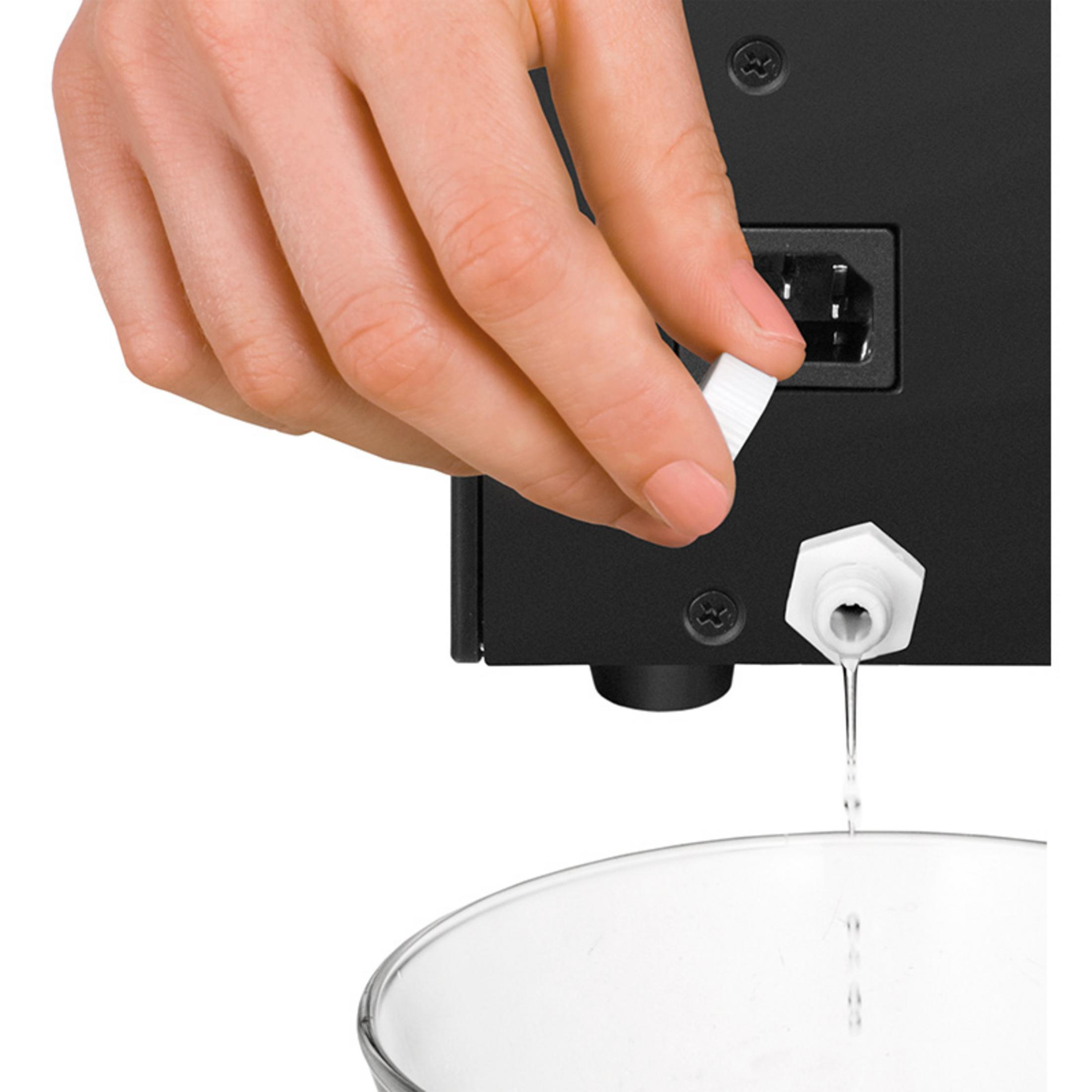 Ręka trzyma białą nakrętkę nad zaworem, z którego kapie woda.