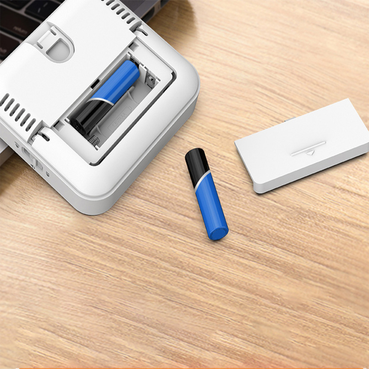 Ein weißes Gerät mit offenem Batteriefach und zwei Batterien. Ein weiteres Gerät liegt daneben.