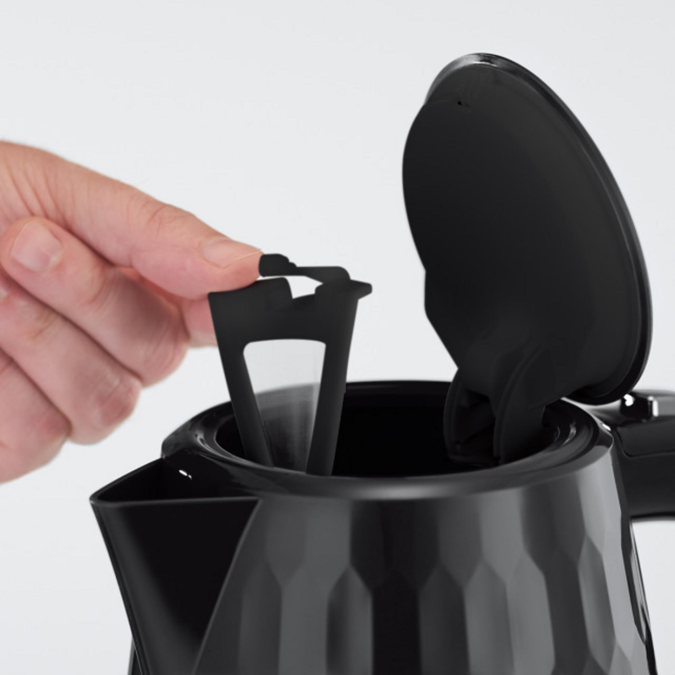 Eine Hand entfernt einen schwarzen Filter aus einem Wasserkocher.