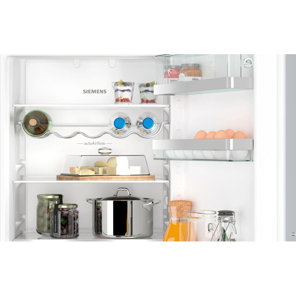 Otwarta lodówka Siemens z żywnością: ser, jajka, słoiki i garnek.
