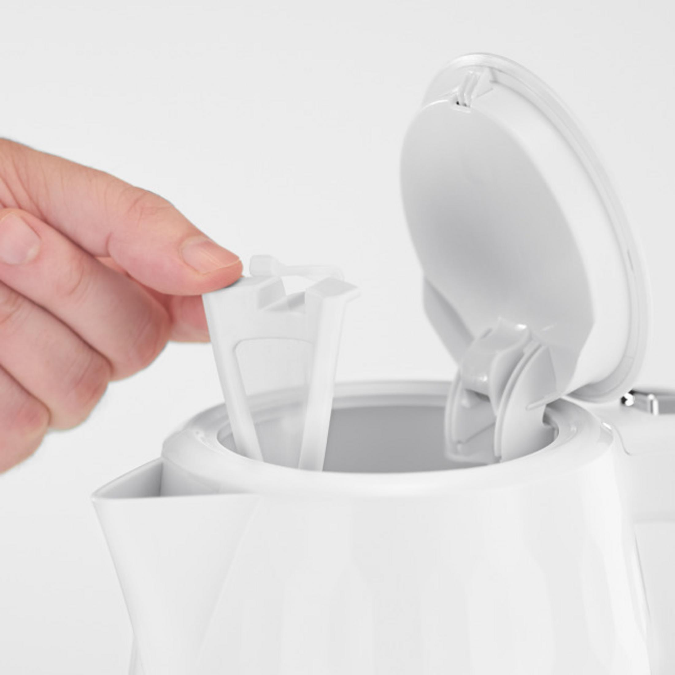 Una mano inserisce un filtro dell'acqua bianco in un bollitore bianco.