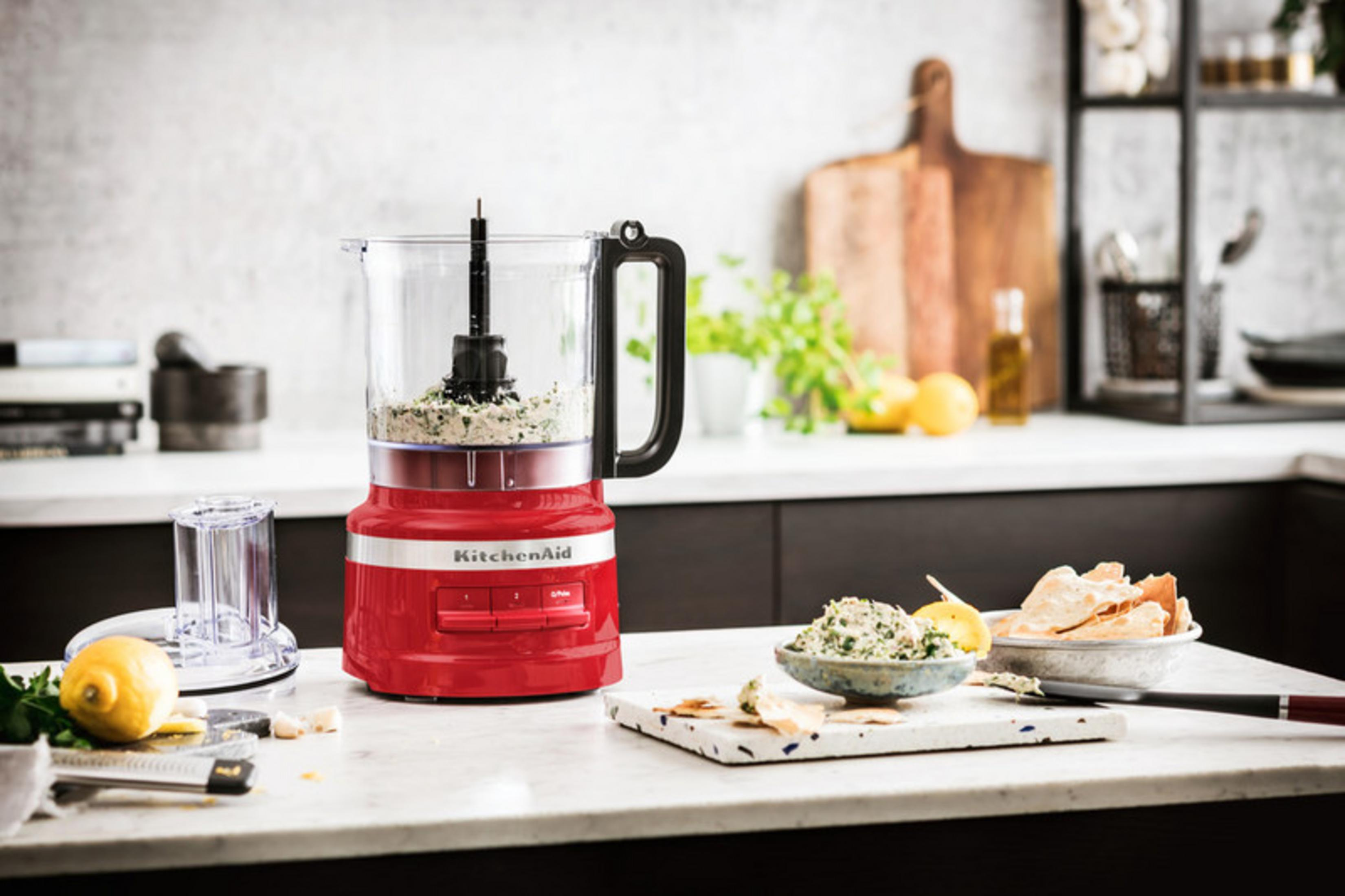 Tezgah üzerinde malzemeleri olan kırmızı bir KitchenAid mutfak robotu.