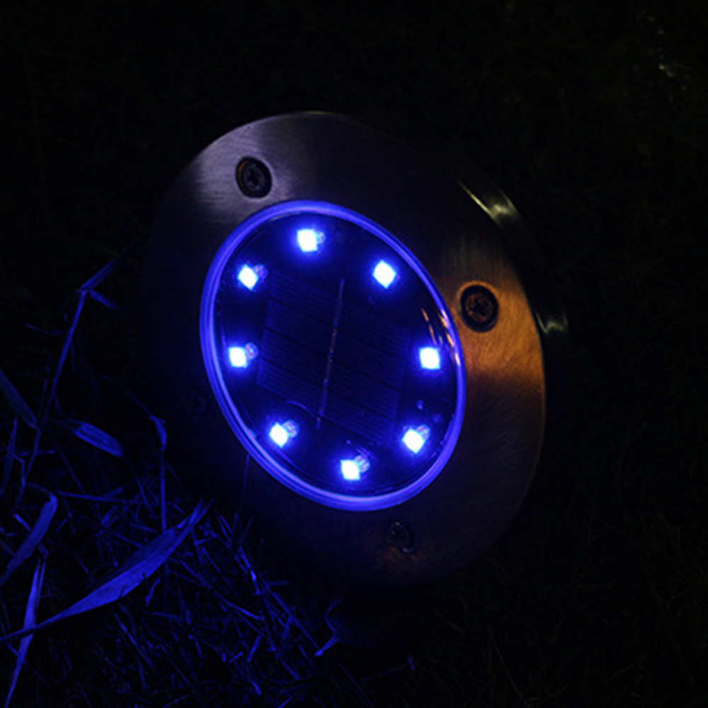 Eine Solarleuchte mit blauen LEDs leuchtet im Dunkeln auf Gras.