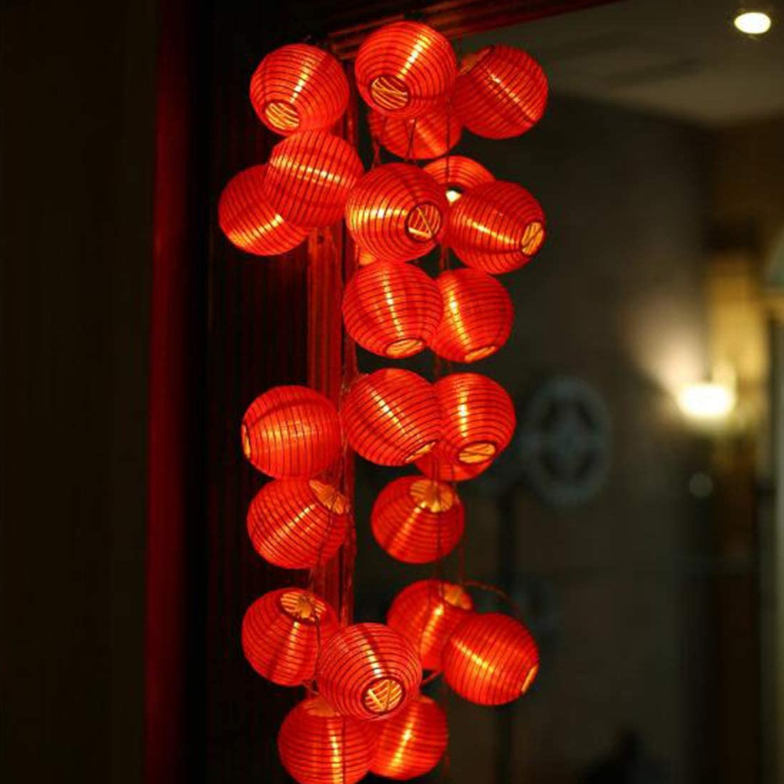 Eine Schnur roter Lampions hängt im Dunkeln, beleuchtet.