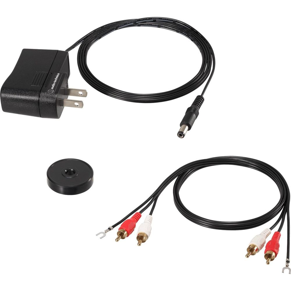 Un adaptador de corriente, un adaptador redondo y un cable de audio con conectores RCA.