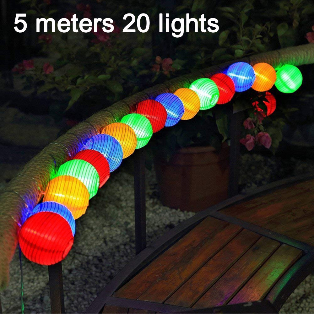 Eine Lichterkette mit bunten Kugellichtern, die auf einem Geländer drapiert ist.