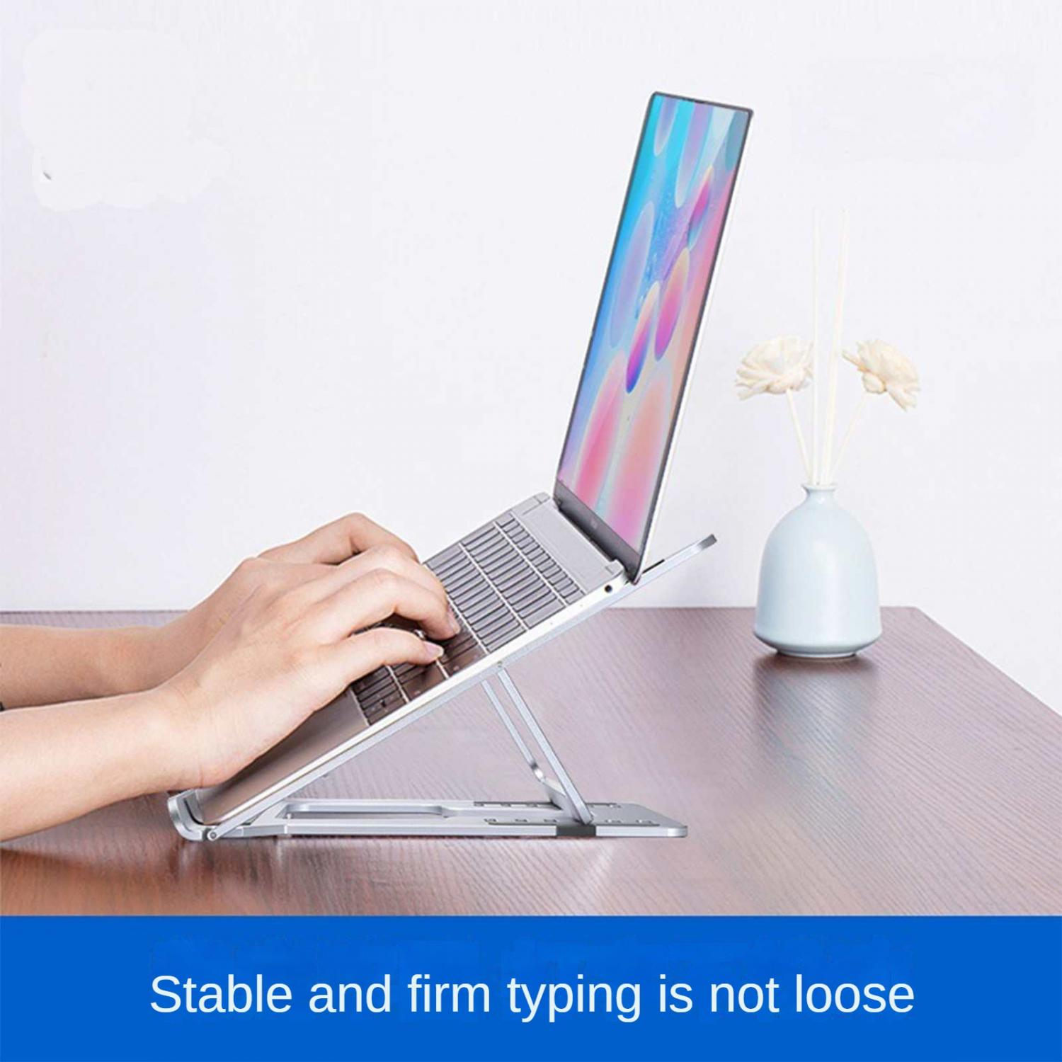 Eine Person tippt auf einem Laptop, der auf einem silbernen Ständer steht.