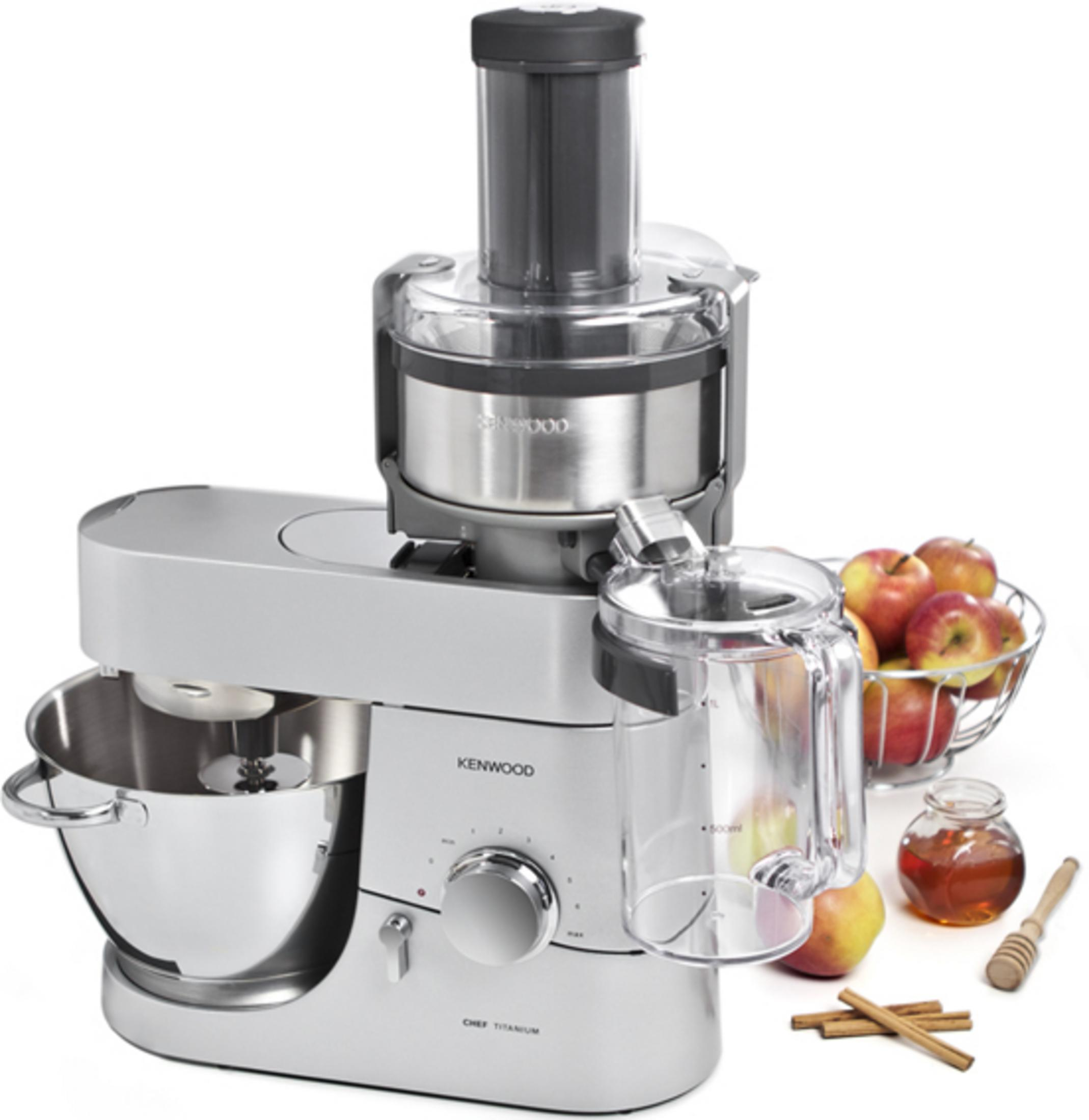 Eine silberne Küchenmaschine mit Schüssel, Saftpresse, Äpfeln, Honig und Zimt.