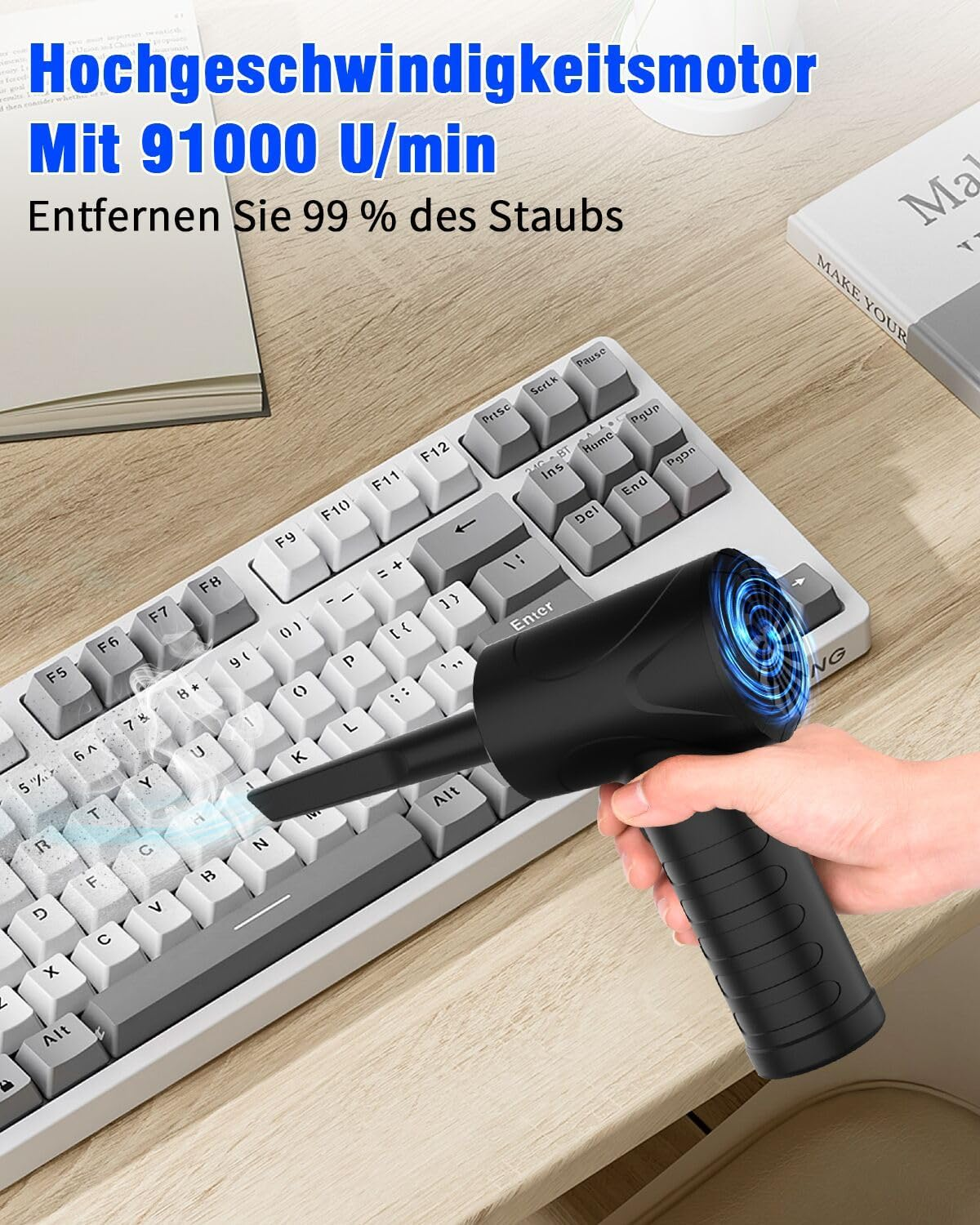 Eine Hand hält einen schwarzen kabellosen Bläser, der Staub von einer Tastatur entfernt.