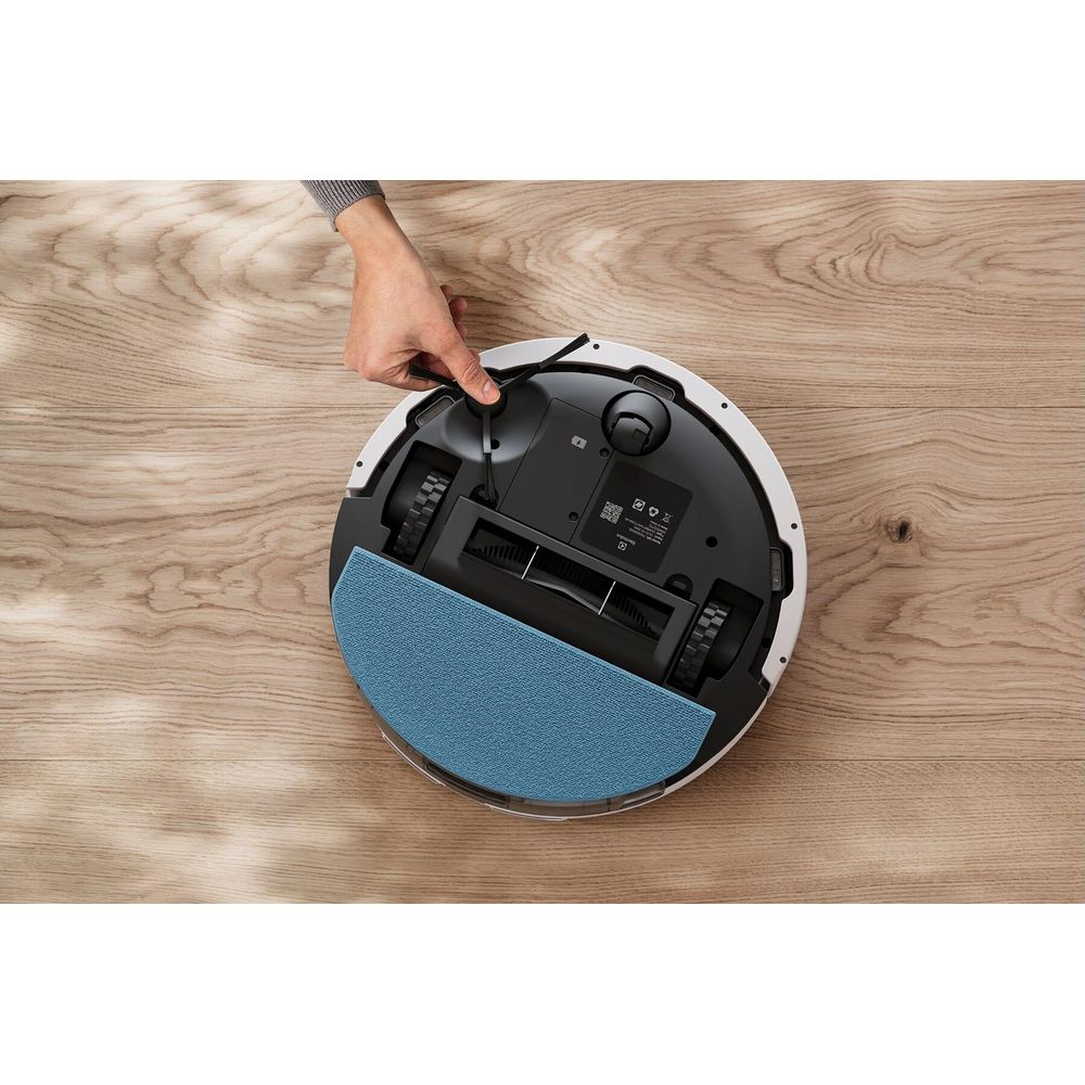 Ein Saugroboter mit einer blauen Wischfunktion auf Holz. Hand befestigt das Kabel.