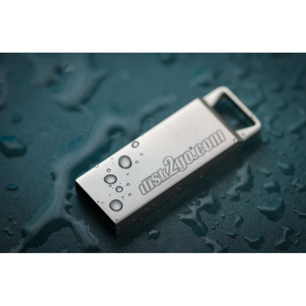 Une clé USB argentée avec des gouttelettes d'eau sur une surface sombre.