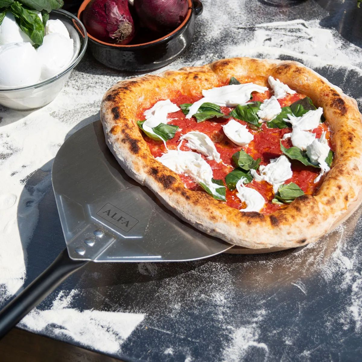 Eine Margherita-Pizza mit Tomaten, Mozzarella und Basilikum auf einem Pizzaschieber.