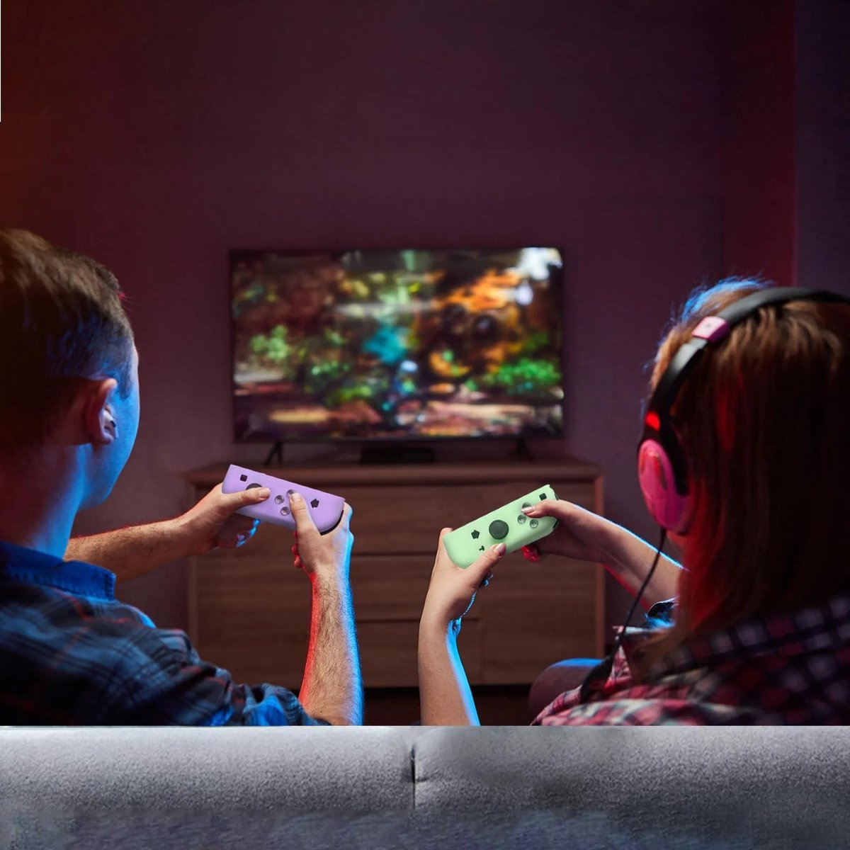 Zwei Personen spielen Videospiele mit Controllern vor einem Fernseher.