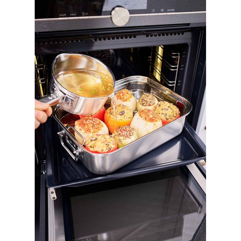 Du liquide est versé dans un plat de cuisson avec des oignons et tomates farcis.