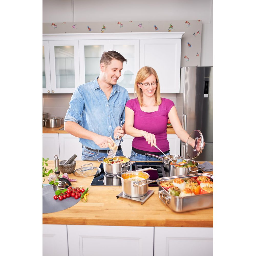 Un homme et une femme cuisinent dans une cuisine avec des casseroles et des poivrons farcis.