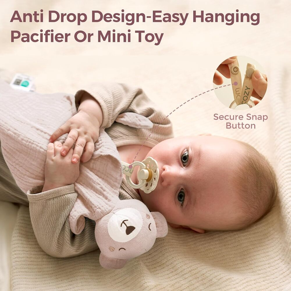 Baby mit Schnuller und Bärenanhänger. Nahaufnahme des sicheren Knopfverschlusses.