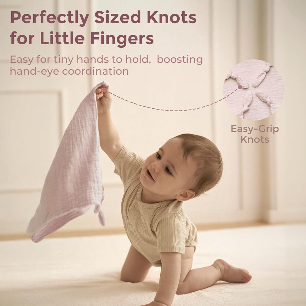Baby kniet und hält ein rosa Stofftuch mit Knoten.