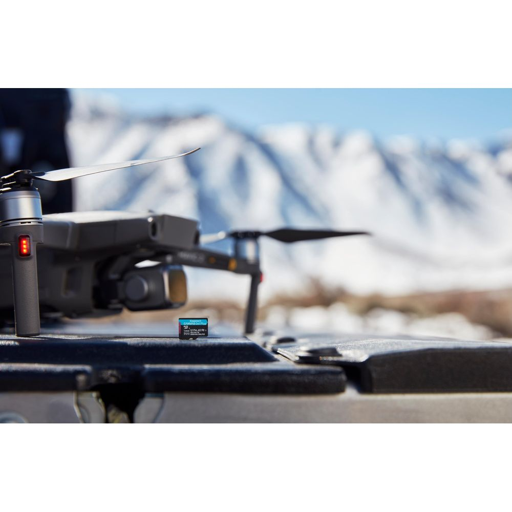 Drone con scheda SD su tavolo davanti a montagne innevate.